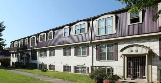 A large apartment building with a lot of windows and a purple roof.