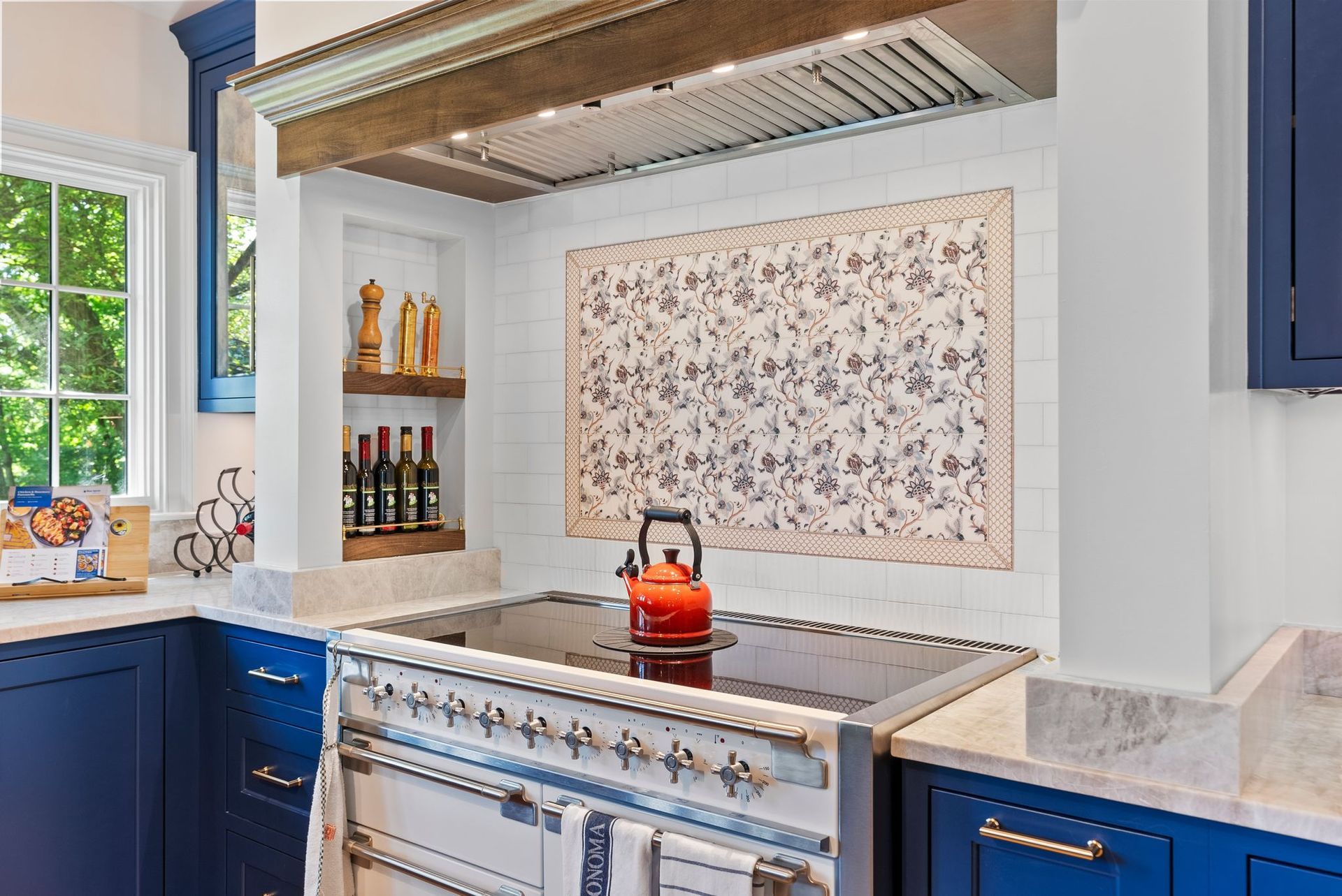 A kitchen with blue cabinets and a stove top oven with a kettle on it.