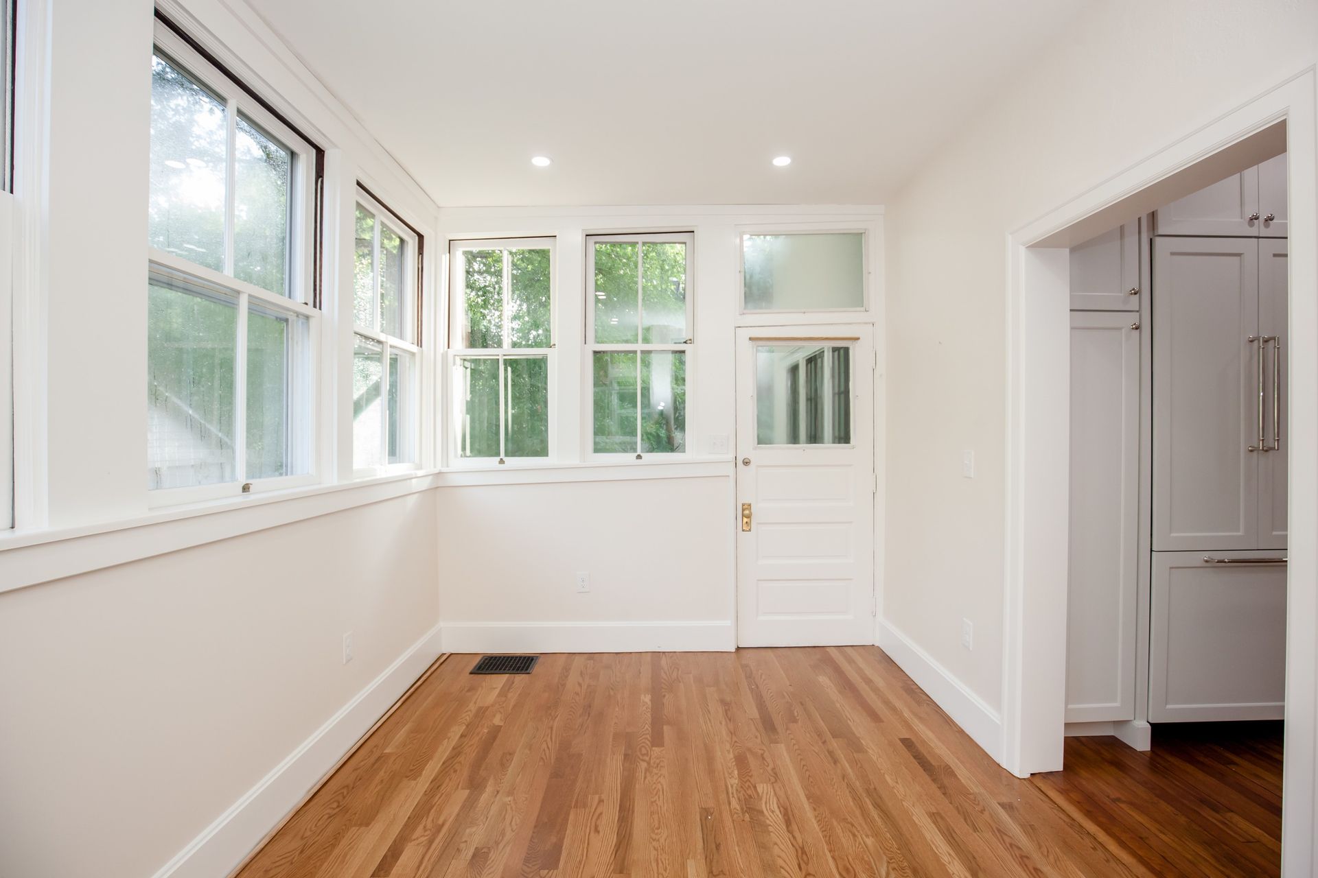 An empty room with hardwood floors and white walls