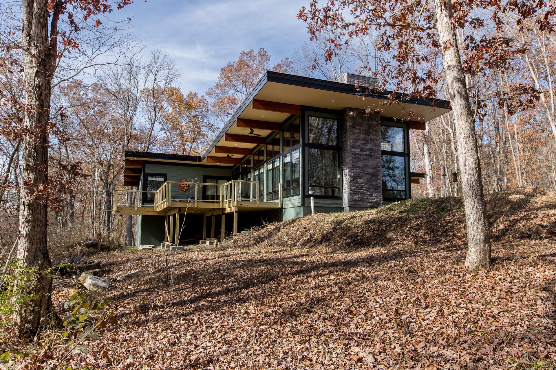 A modern house is sitting on top of a hill in the middle of a forest.