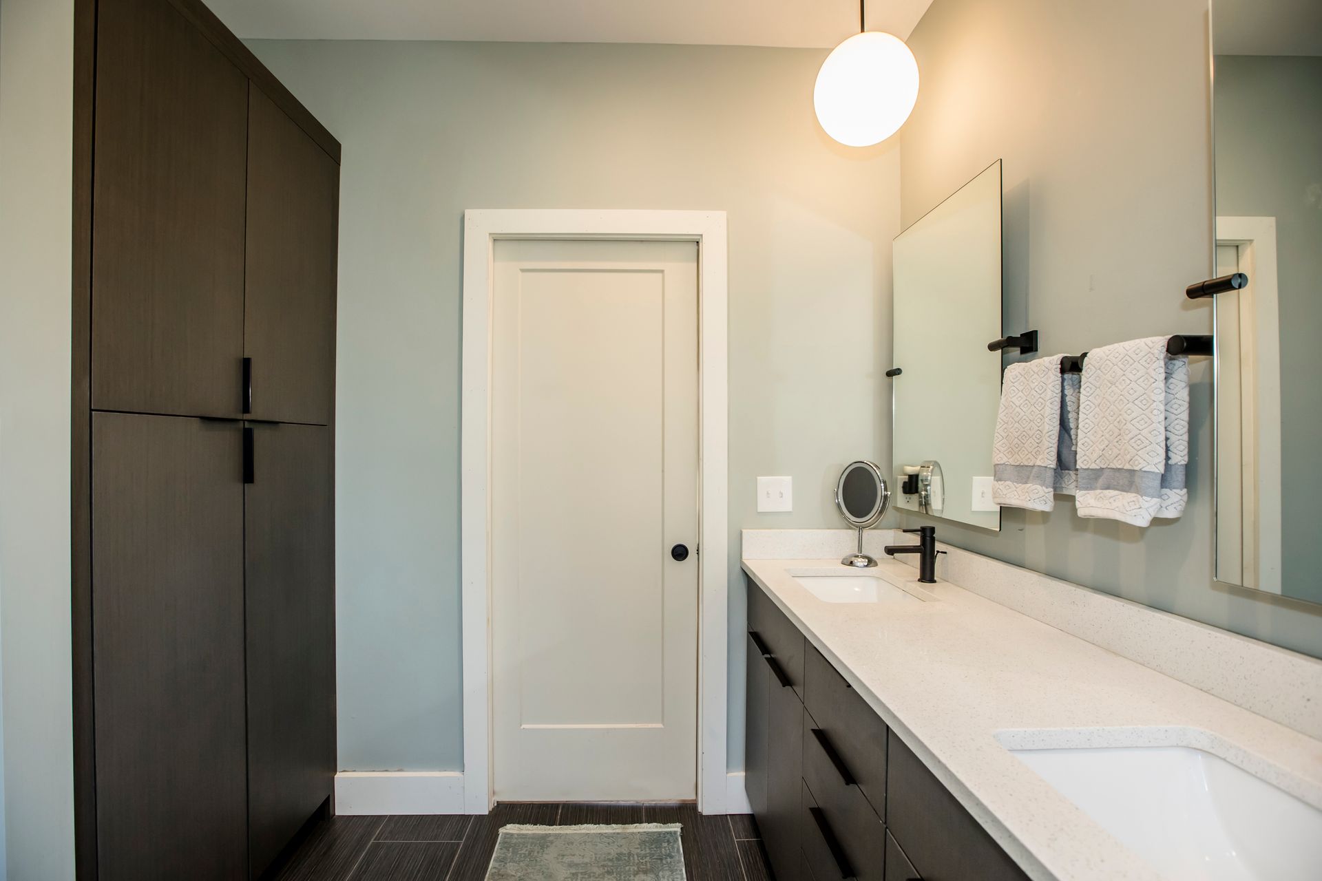 A bathroom with two sinks , a mirror , and a door.