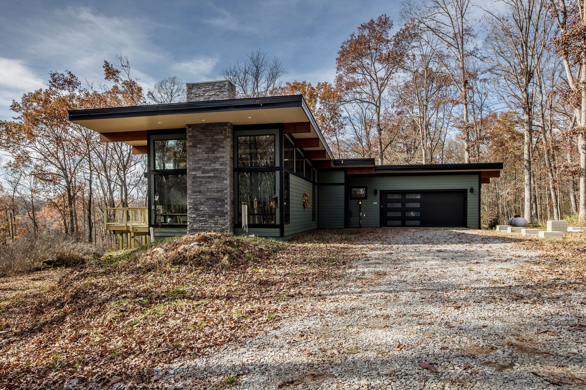 A modern house is sitting on top of a hill in the middle of a forest.