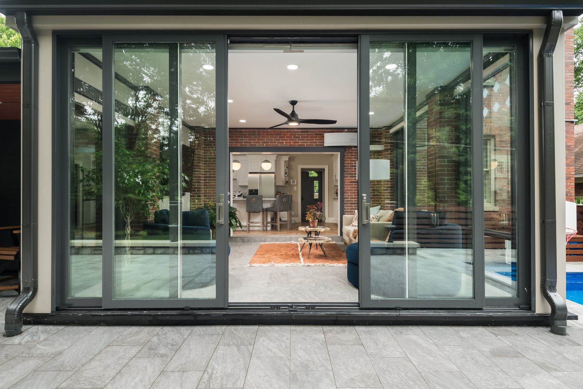A sliding glass door opens to a living room with a ceiling fan.