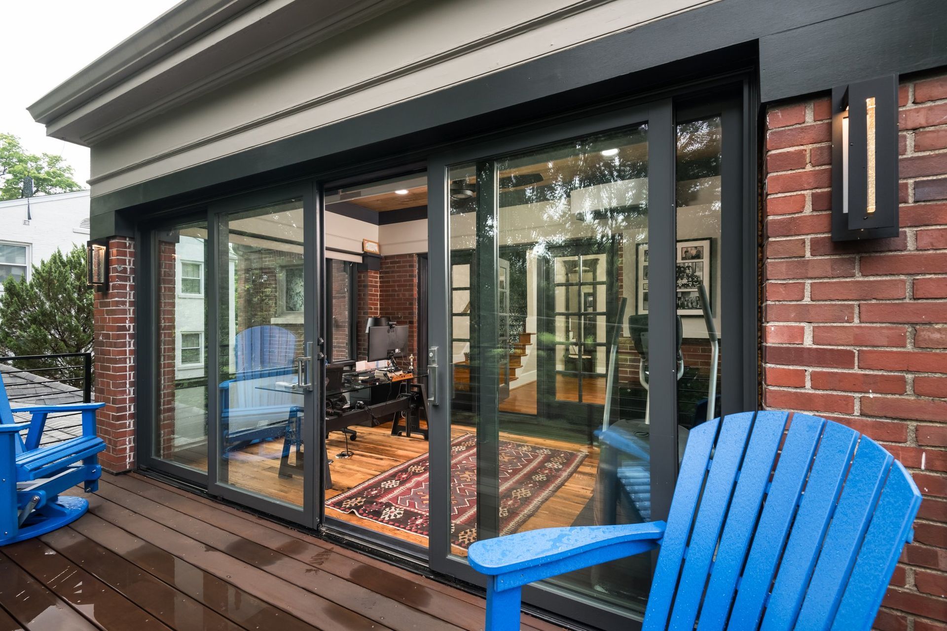 A blue chair is sitting on a wooden deck in front of a brick building.