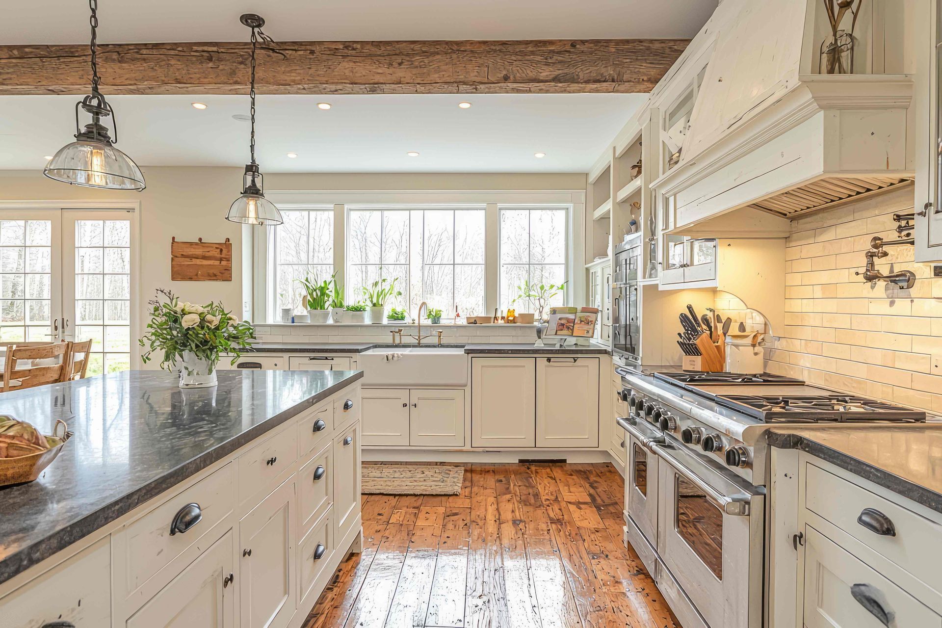 A kitchen with white cabinets , a stove , a sink , and a large island.