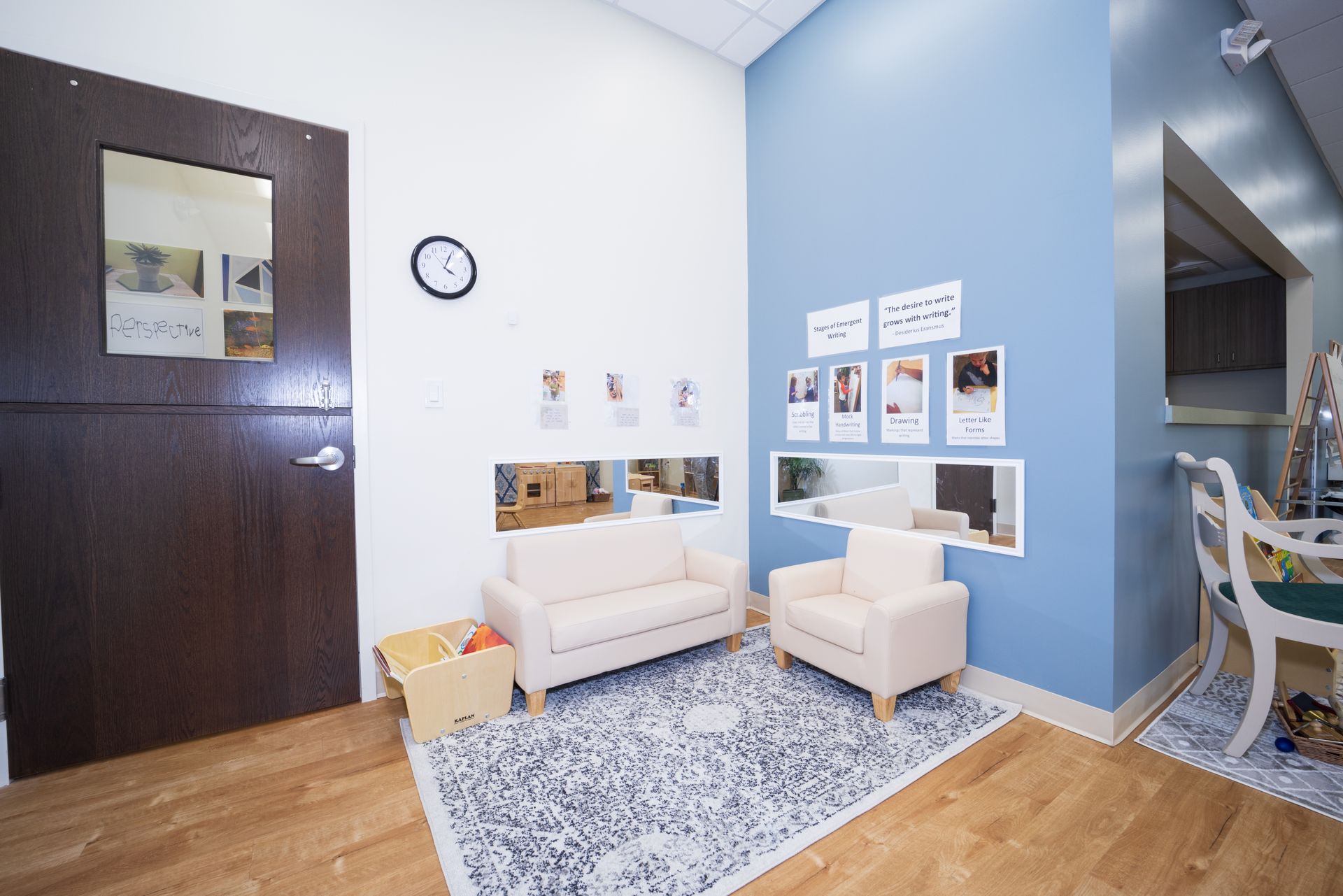 A living room with a couch and chairs and a clock on the wall.