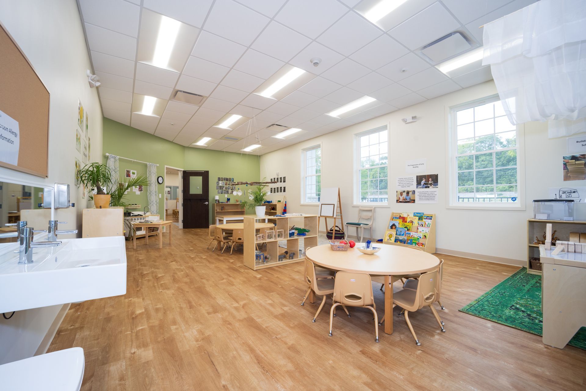 A large classroom with tables and chairs and a sink.