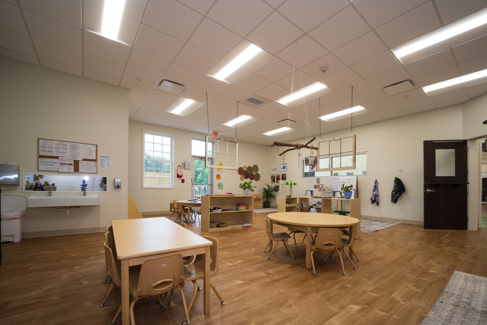 A large classroom with tables and chairs and a sink.