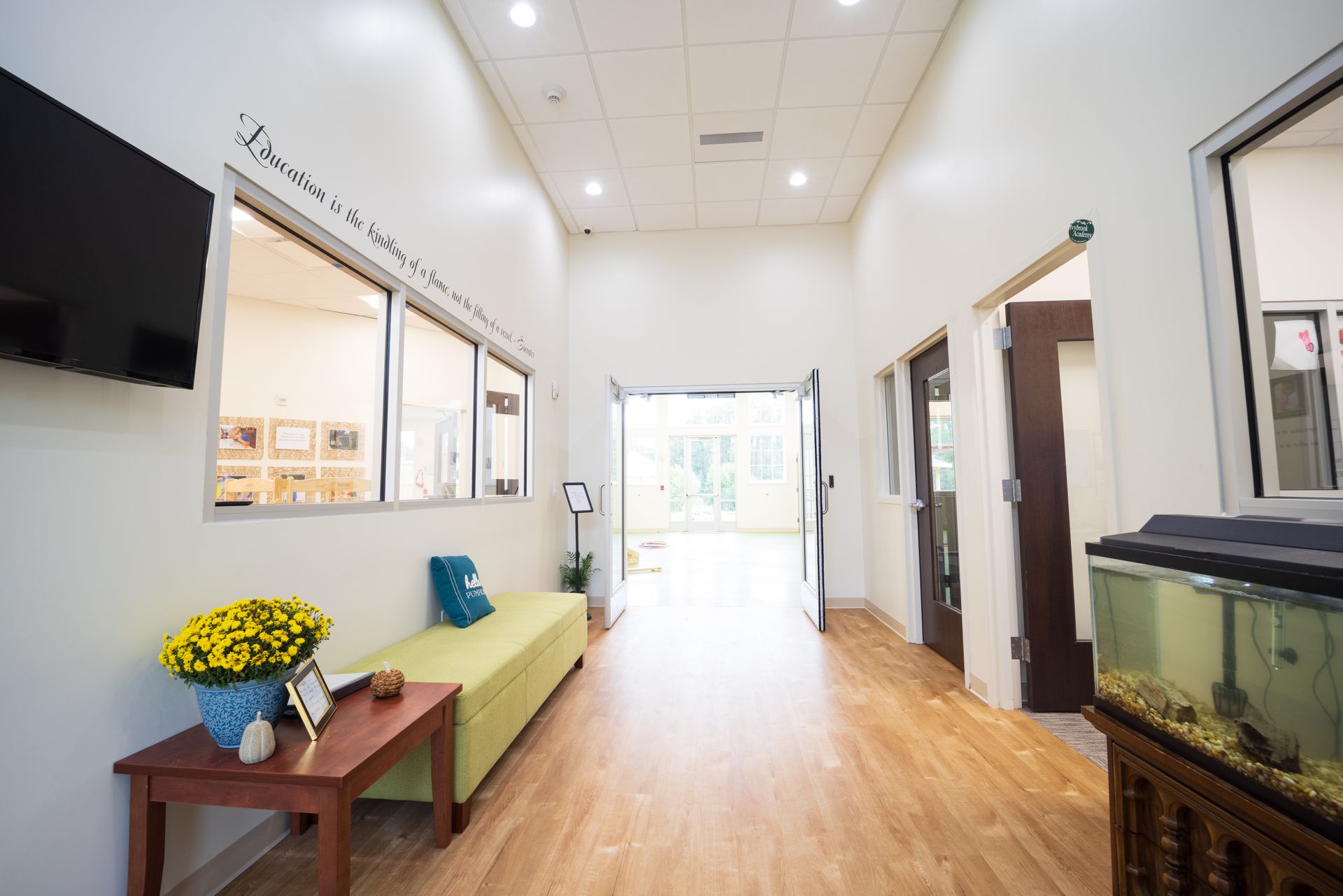 A long hallway with a couch , table , television and fish tank.