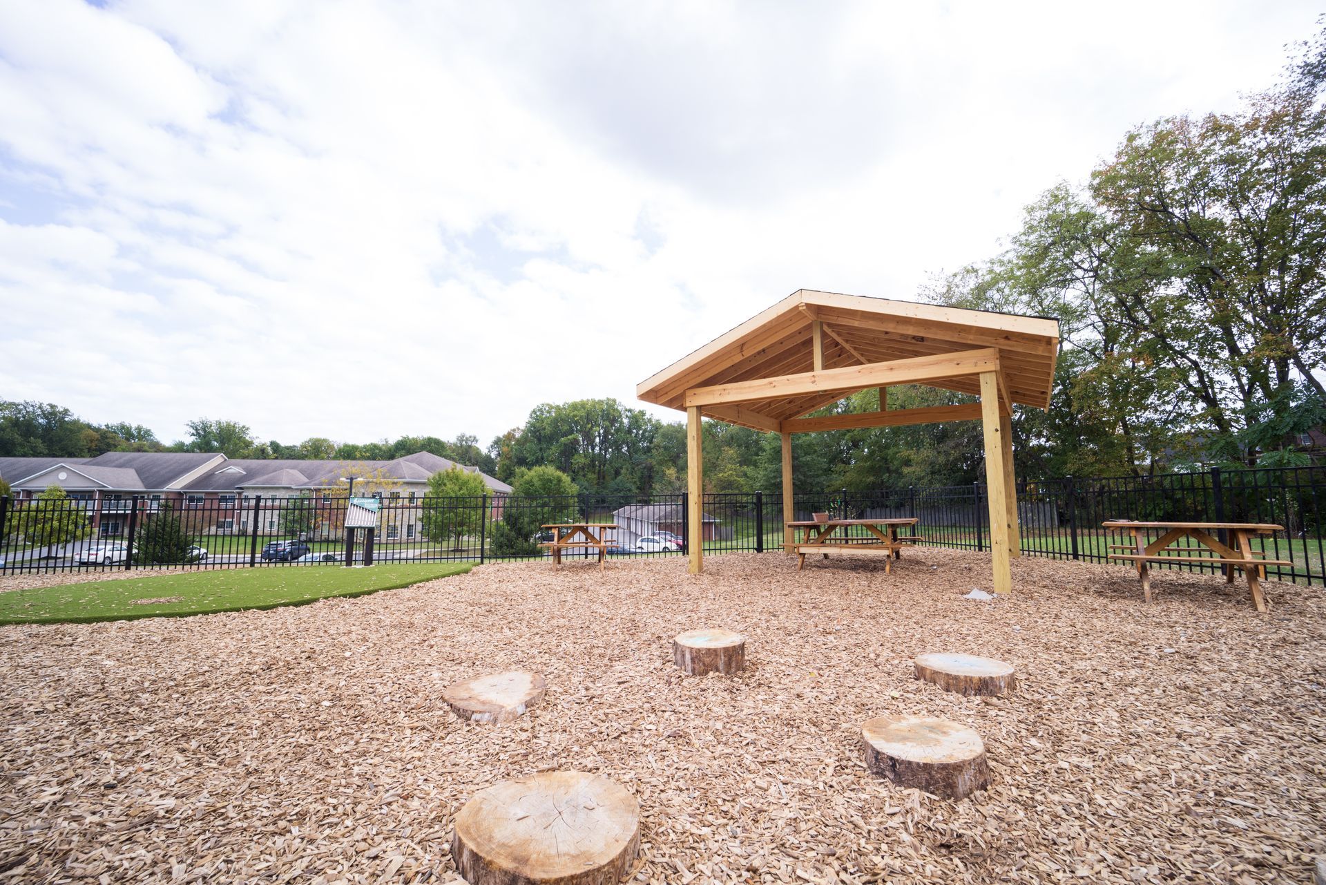 A wooden pavilion is sitting in the middle of a park.