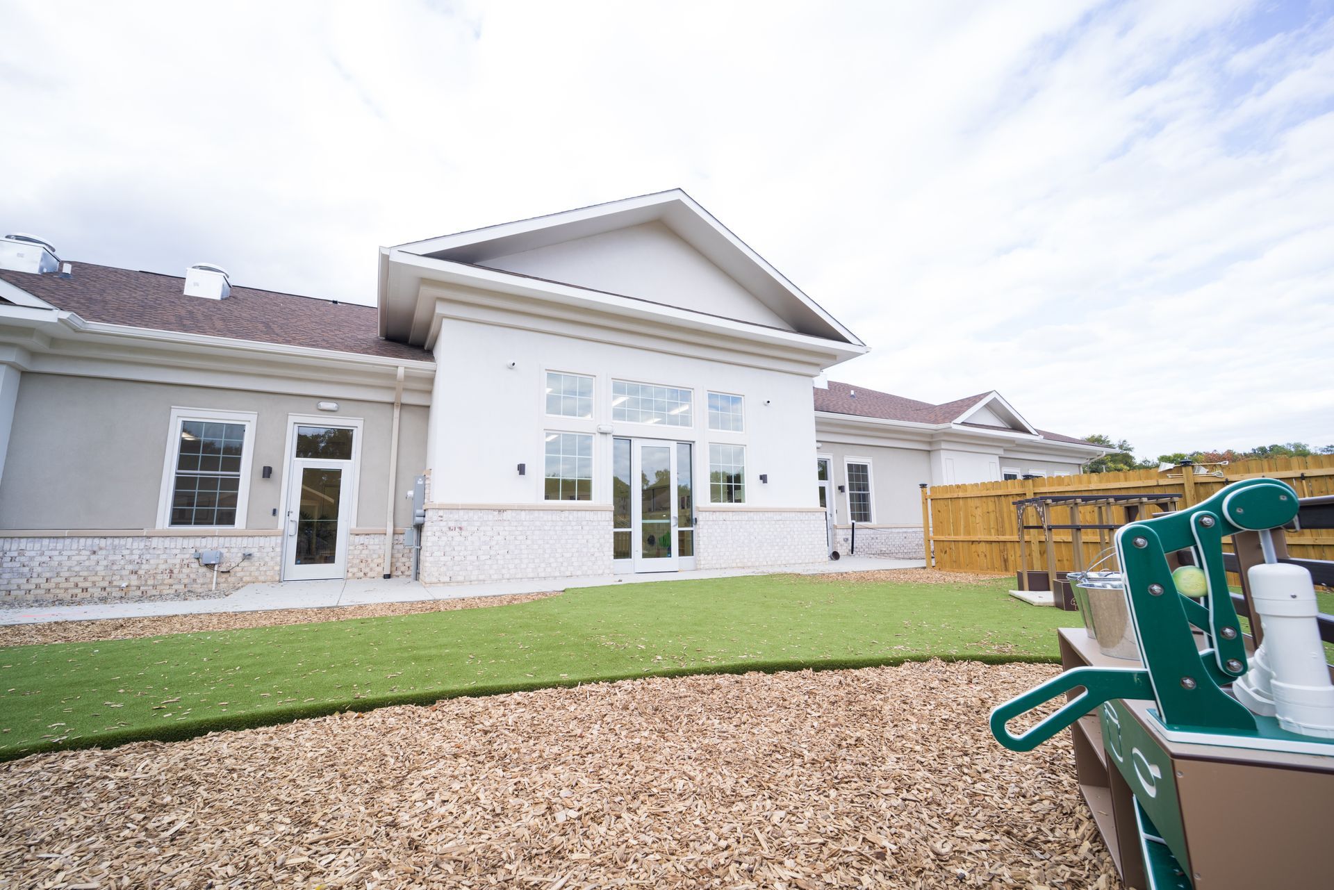 A large white house with a playground in front of it.