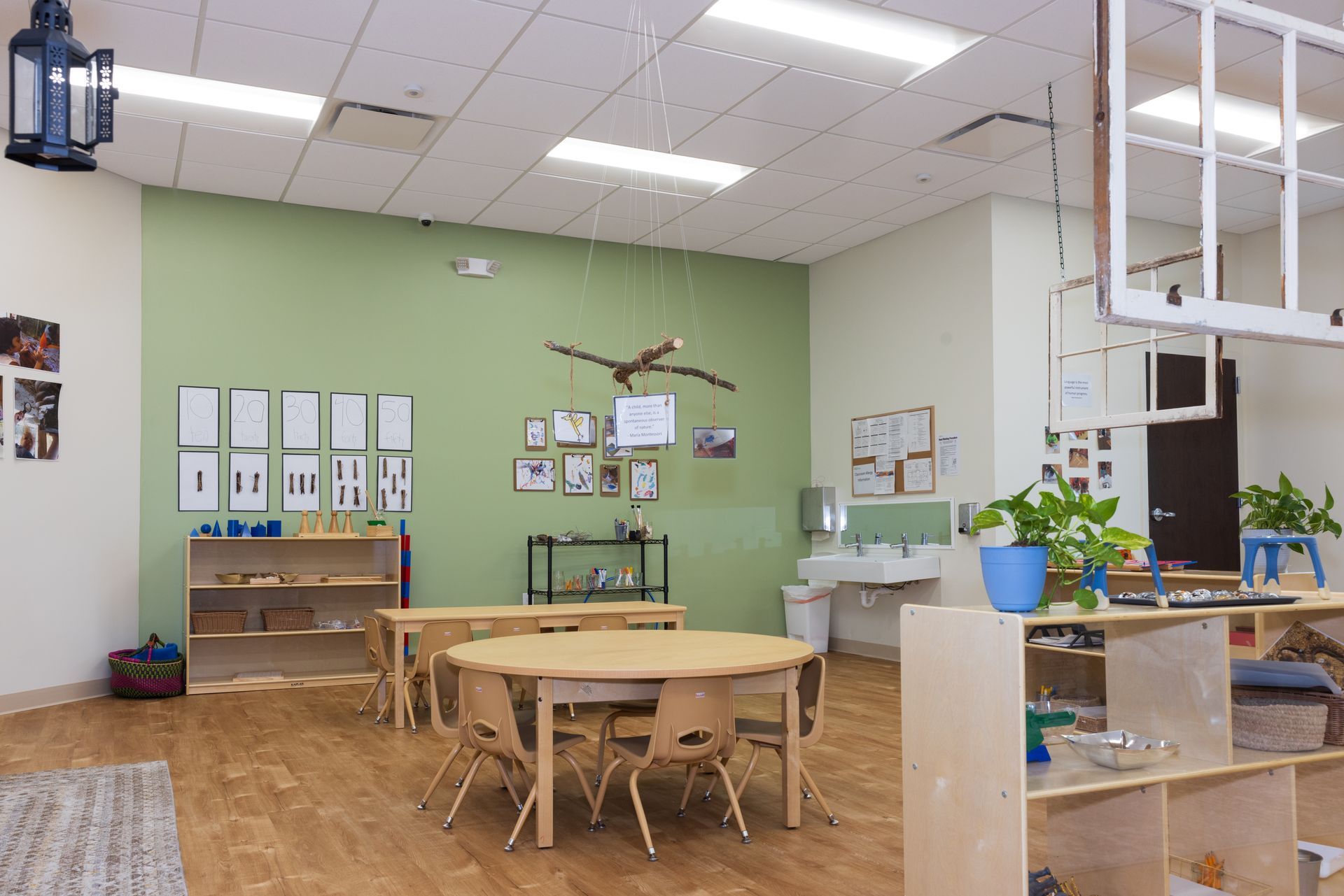 A classroom with tables and chairs and a window hanging from the ceiling.