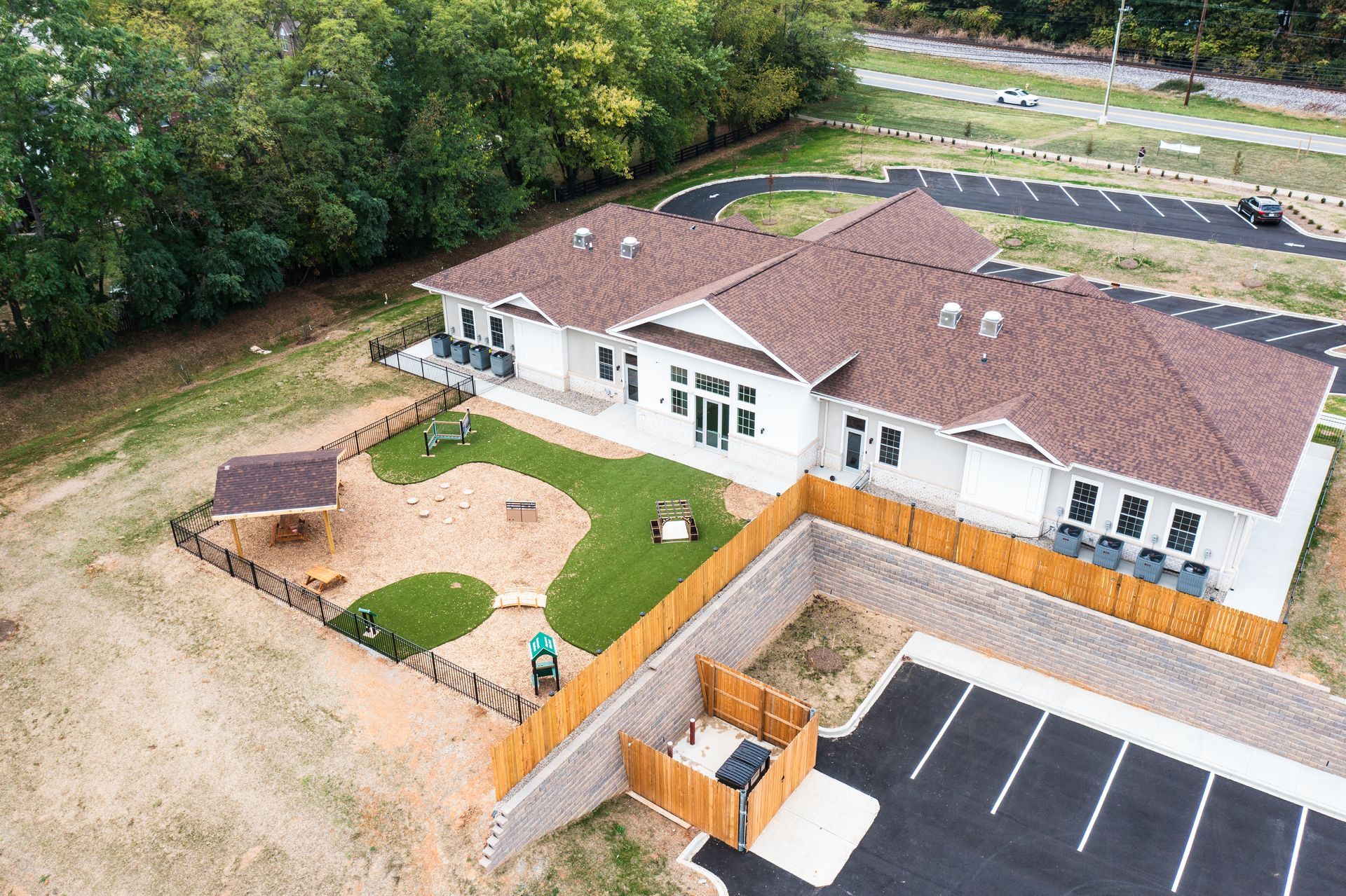 An aerial view of a house with a fence around it and a parking lot.