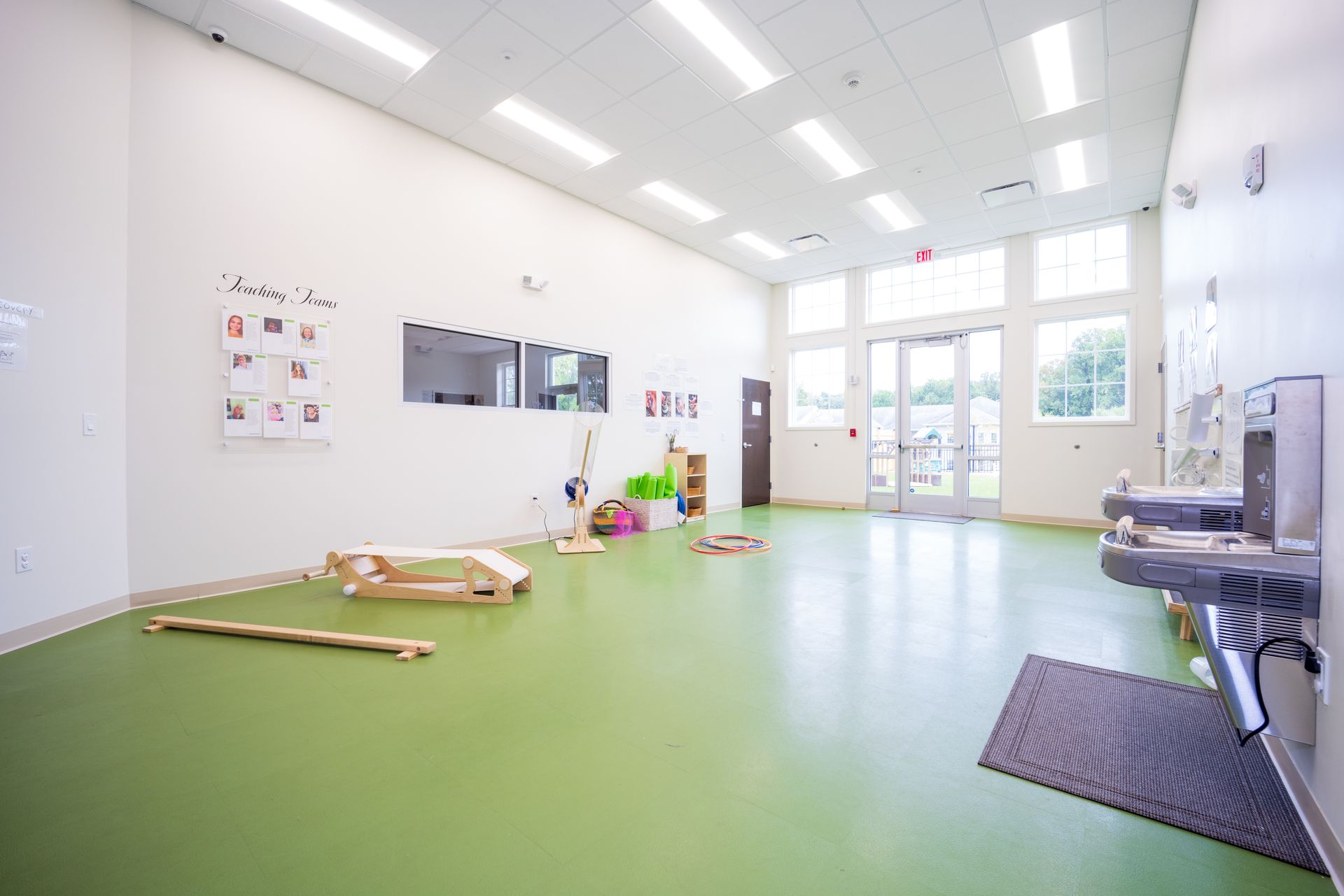 A large empty room with a green floor and a sink.