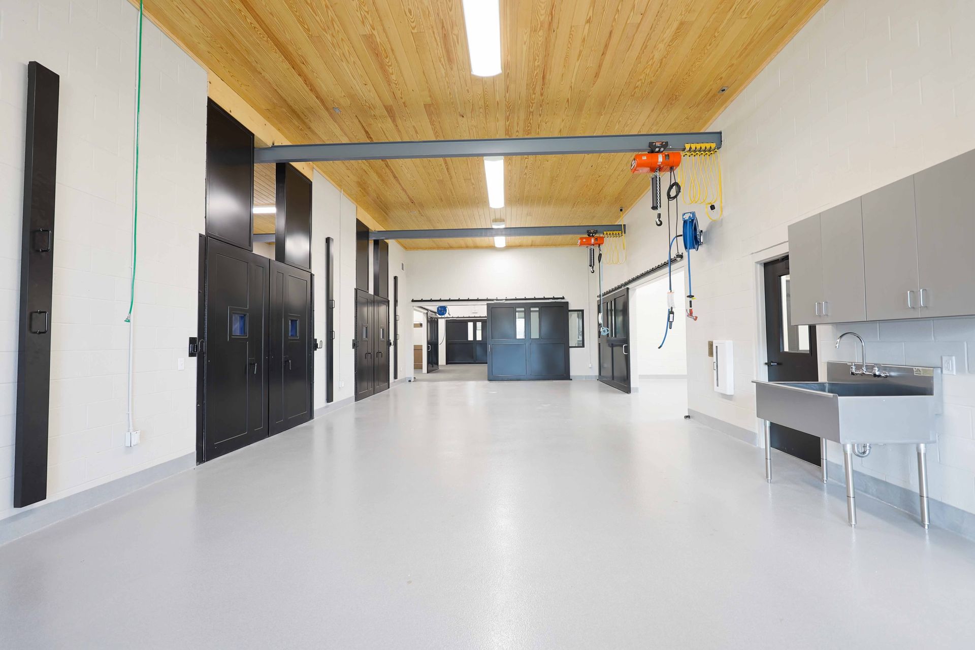 A large empty room with a sink and a crane in the ceiling.