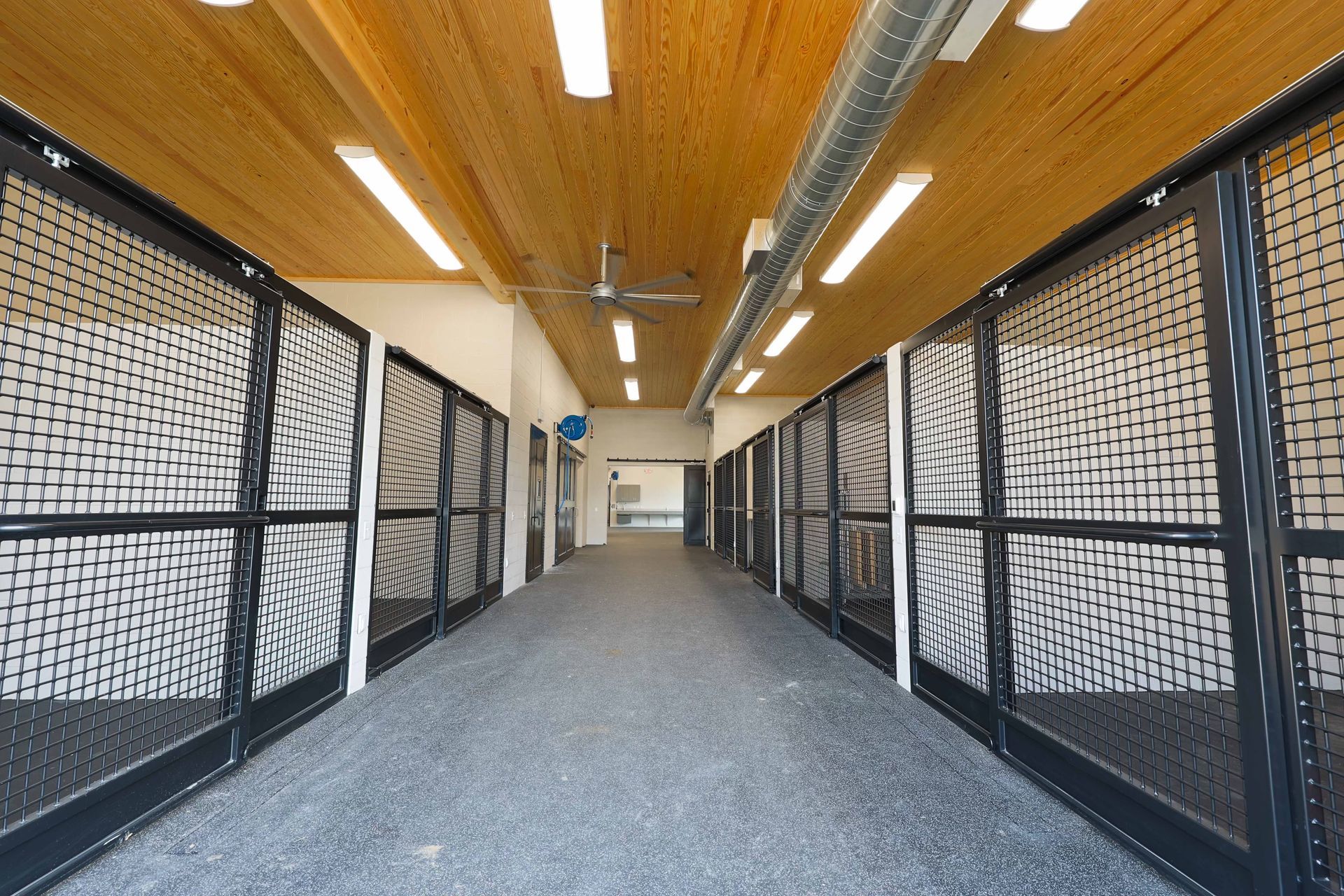 A long hallway with a lot of fences and a ceiling fan