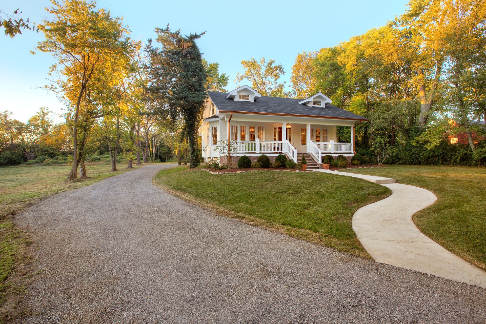 A white house with a porch and a gravel driveway