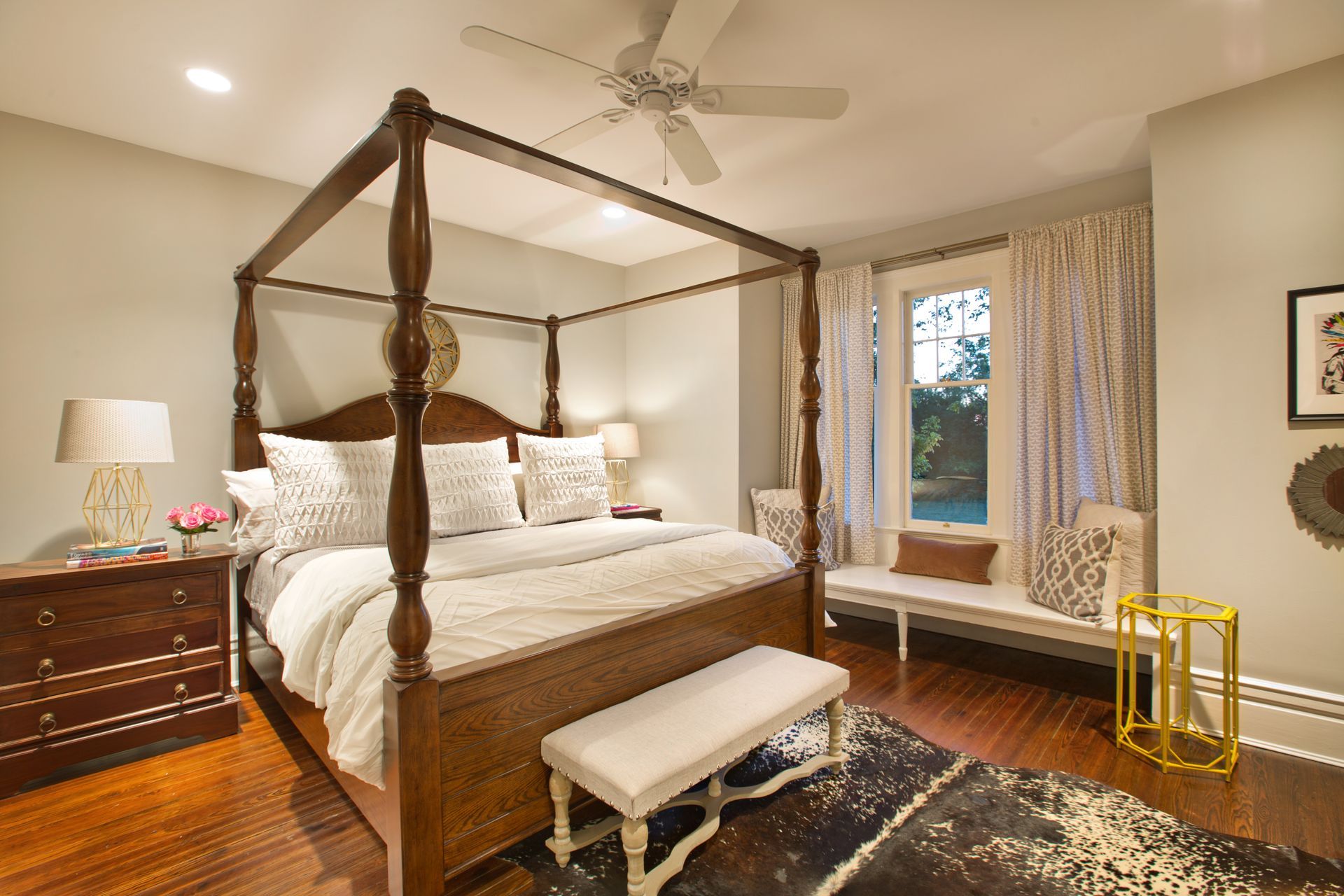 A bedroom with a four poster bed and a ceiling fan