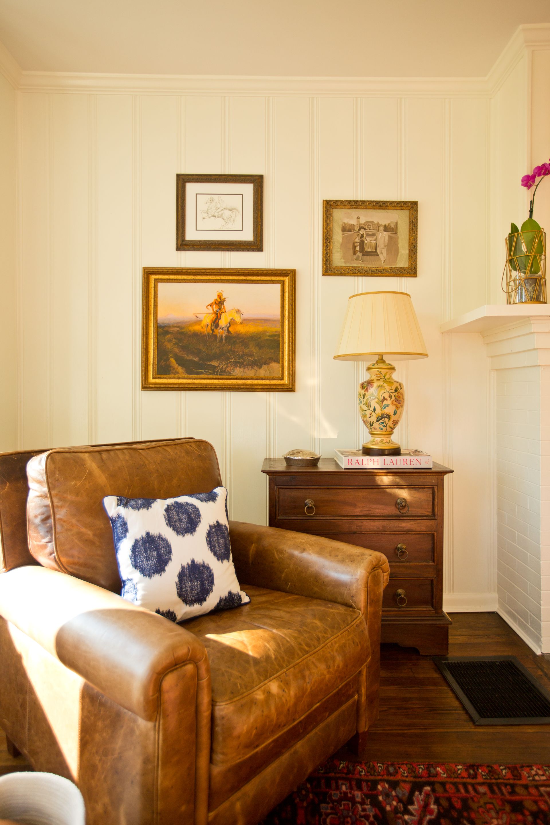 A living room with a brown leather chair and a lamp.