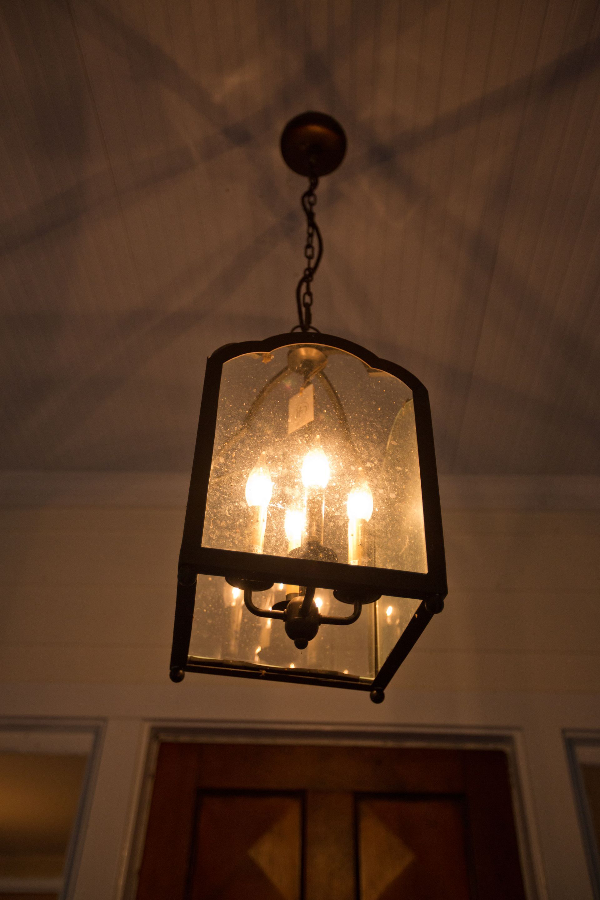 A lantern with candles inside of it is hanging from the ceiling