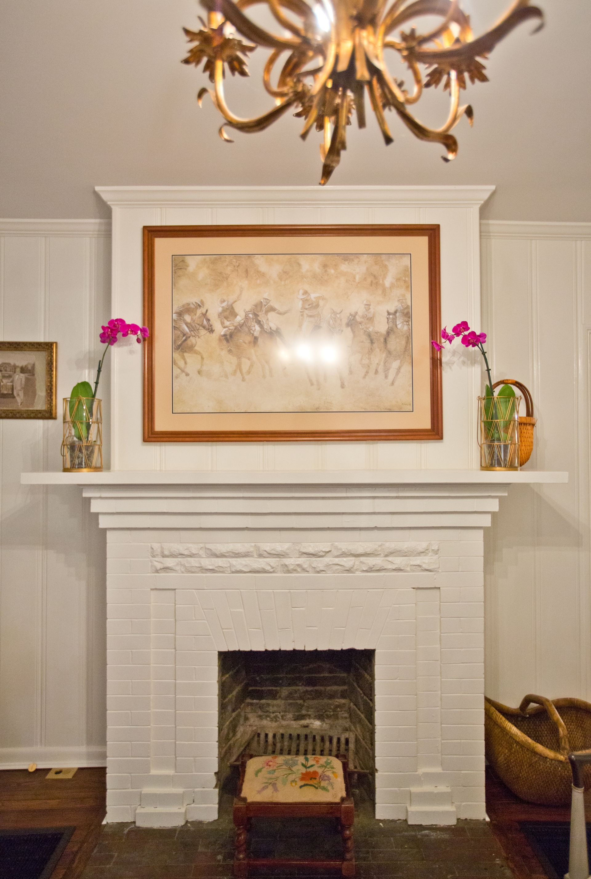 A fireplace with a picture of horses on the wall above it
