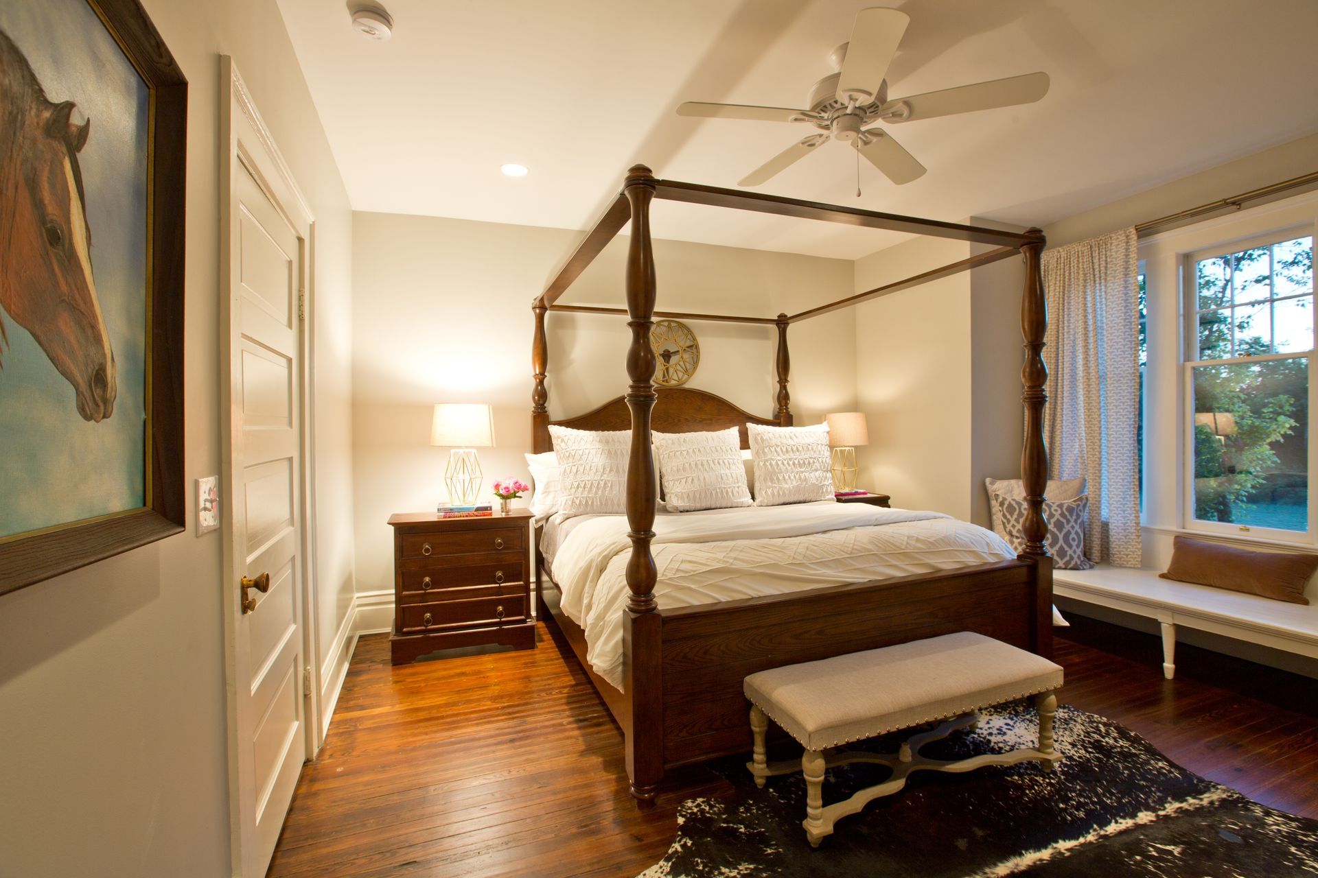 A bedroom with a four poster bed and a ceiling fan