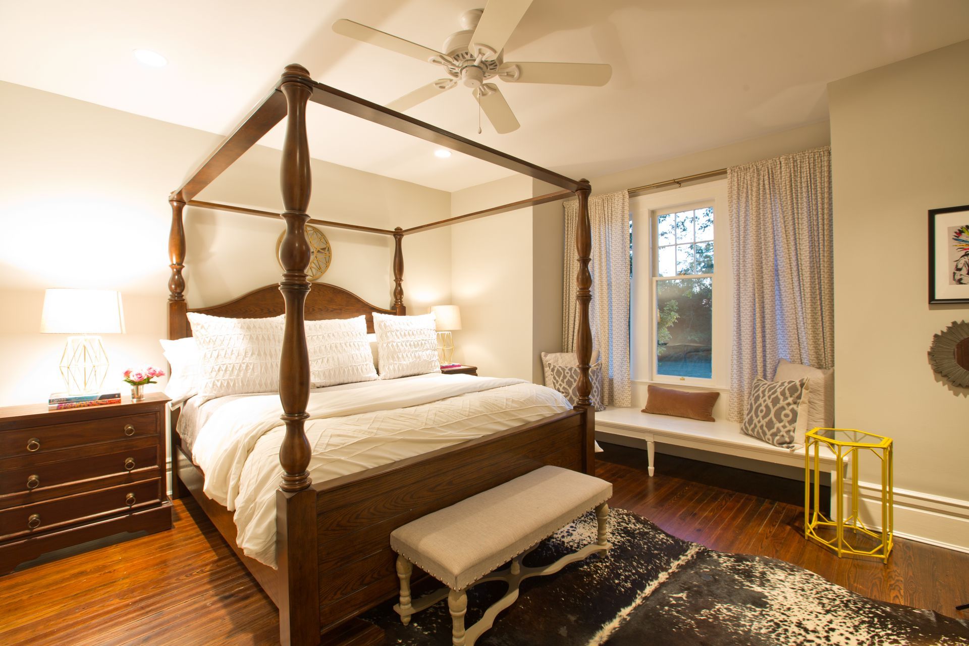 A bedroom with a four poster bed and a ceiling fan