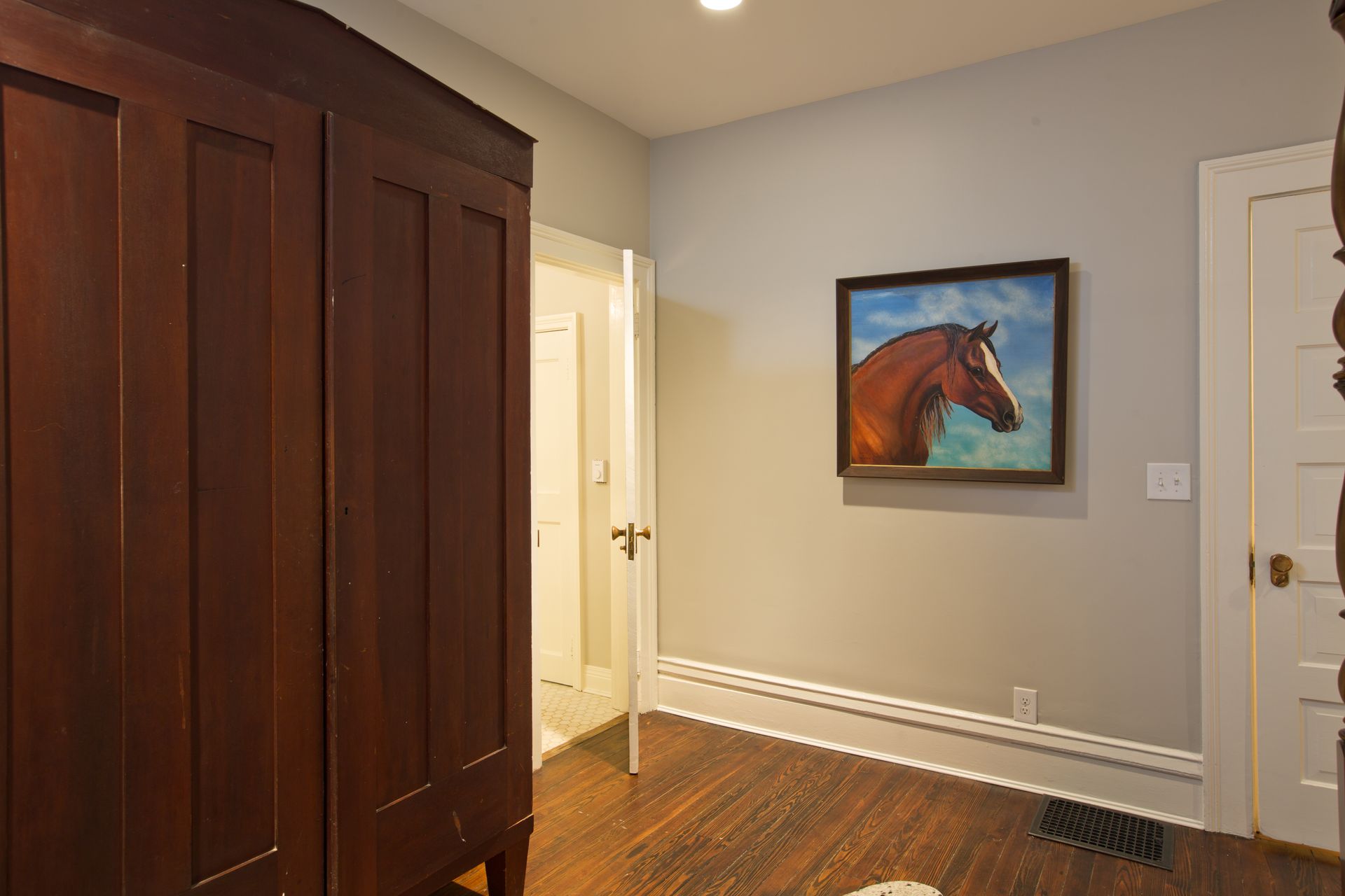 A room with a painting of a horse on the wall.