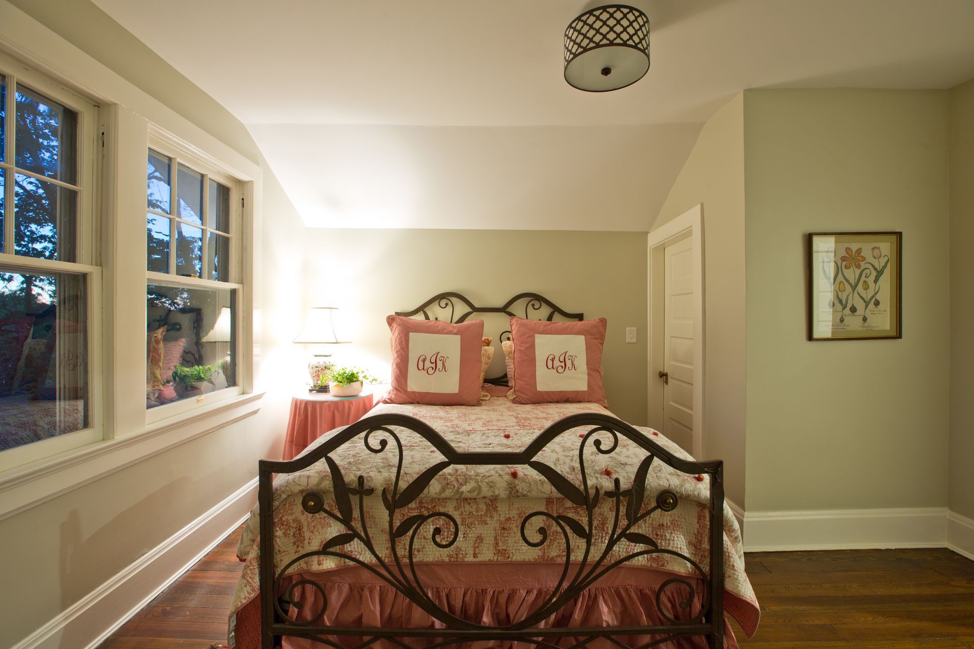 A bedroom with a wrought iron bed and two windows