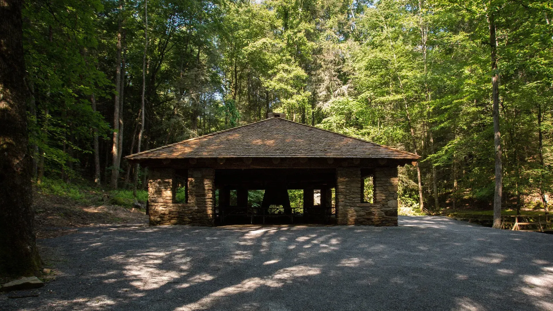 A stone building in the middle of a forest surrounded by trees.