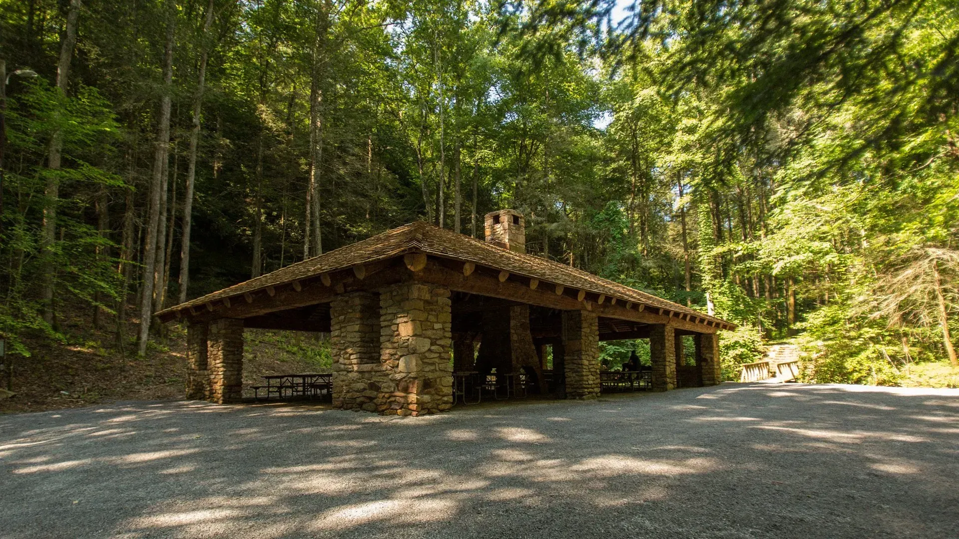A stone pavilion in the middle of a forest surrounded by trees.