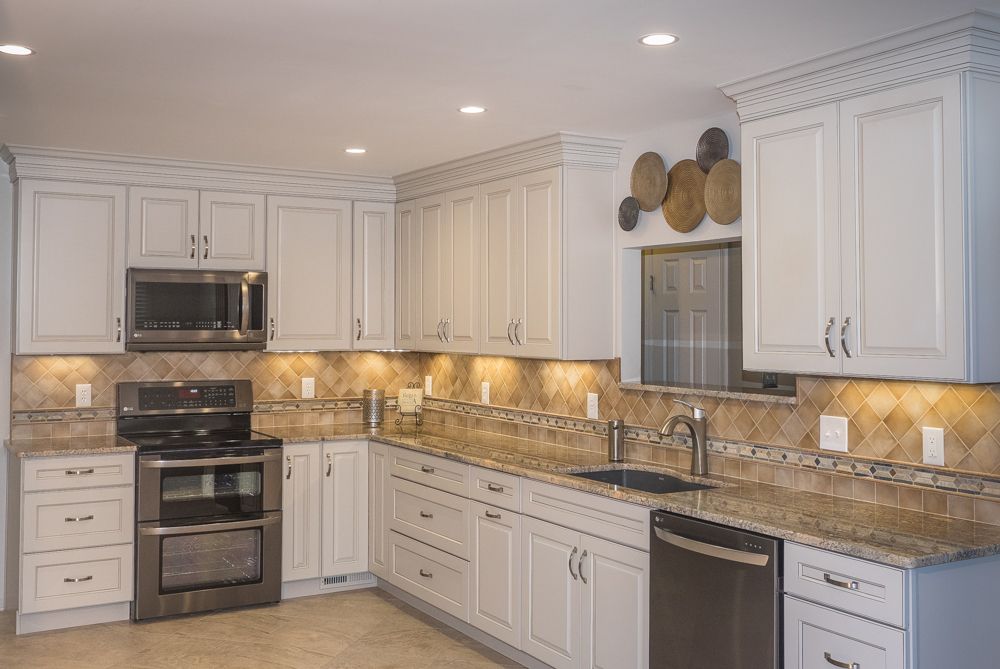 A kitchen with white cabinets , granite counter tops , stainless steel appliances and a stove.