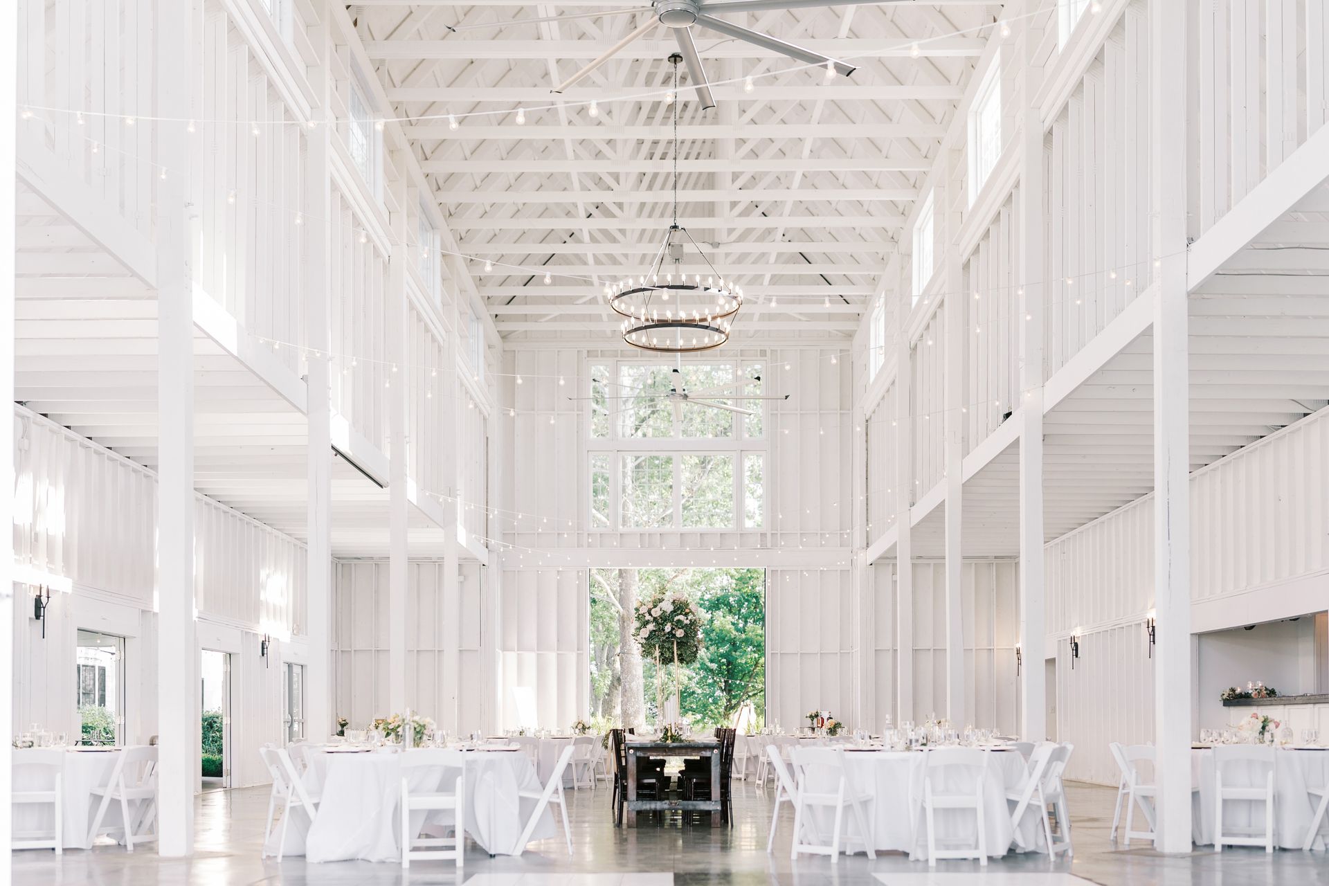 A large white barn with tables and chairs set up for a wedding reception.