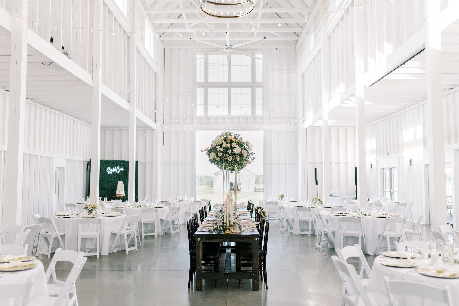 A large white barn filled with tables and chairs for a wedding reception.