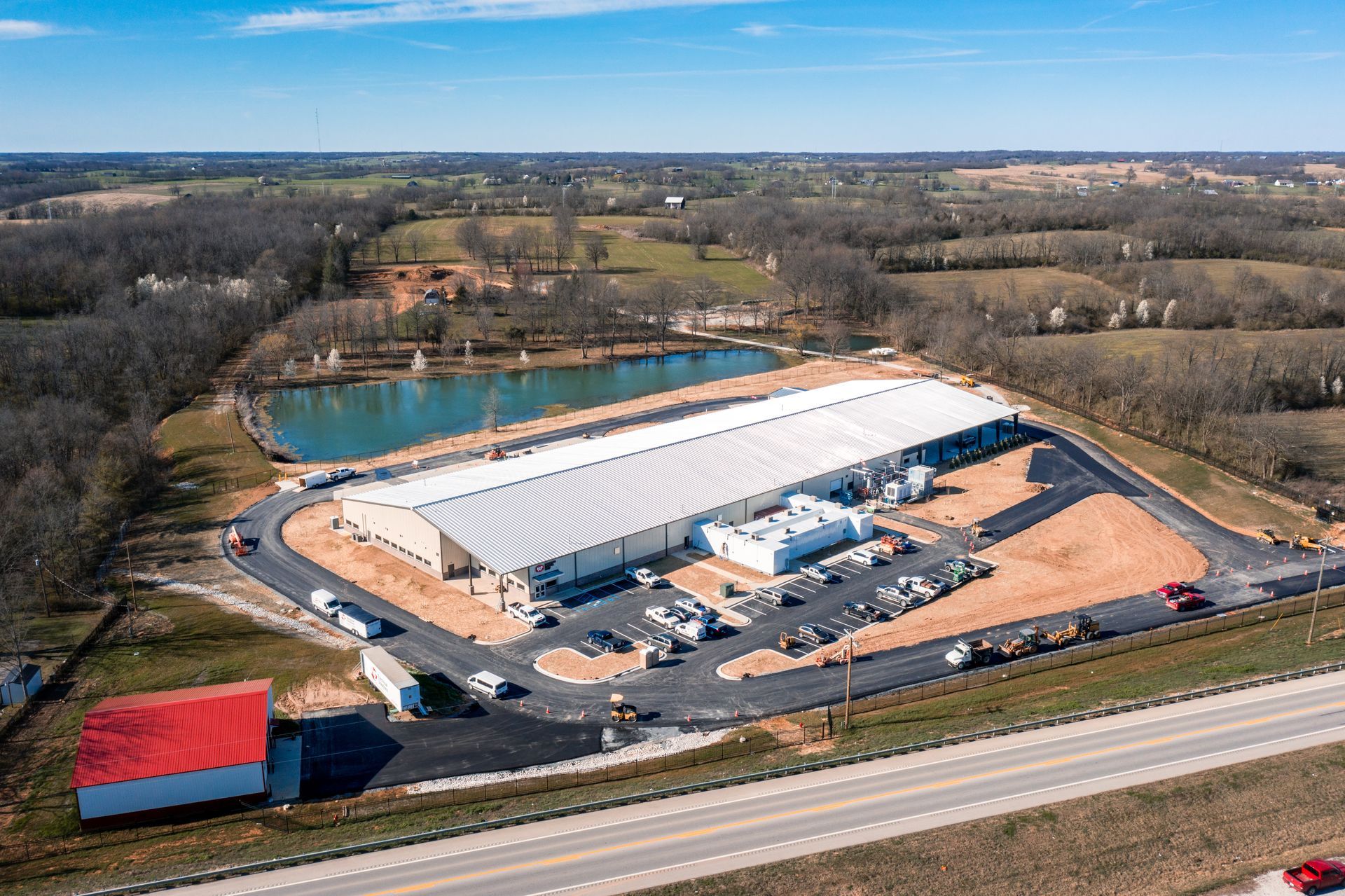 An aerial view of a large building with a red roof next to a highway.