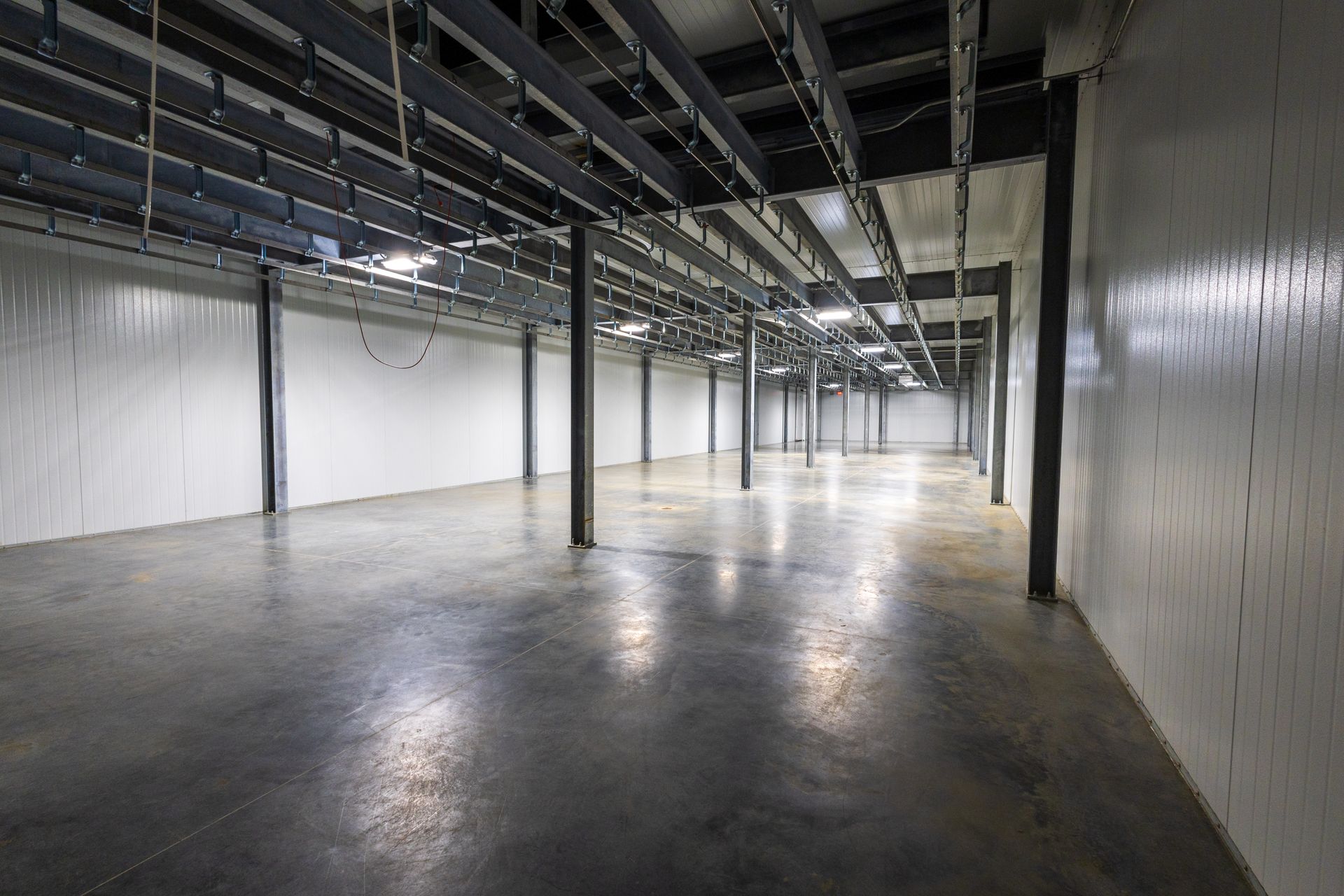 A large empty warehouse with concrete floors and white walls.