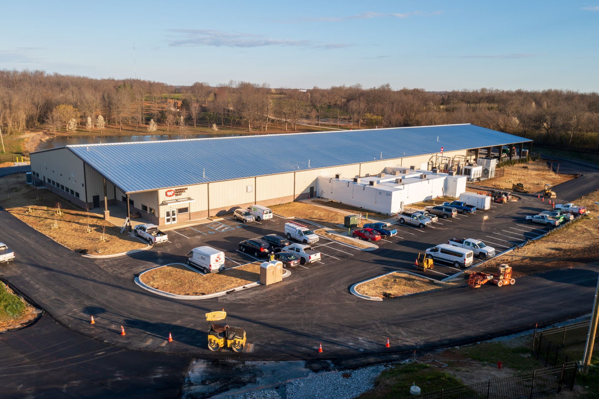 An aerial view of a large building under construction with a lot of cars parked in front of it.