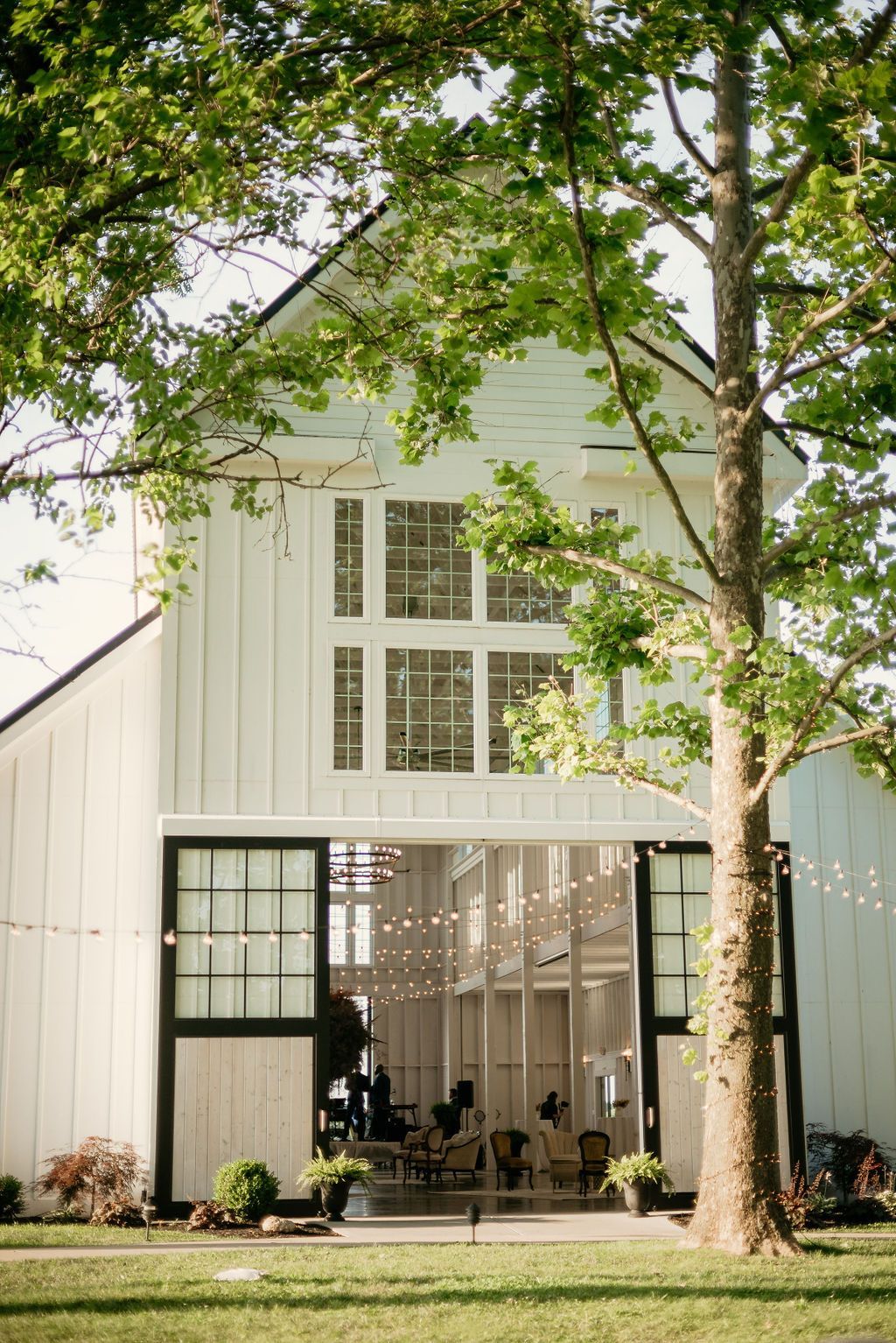 A white barn with a carousel inside of it surrounded by trees.
