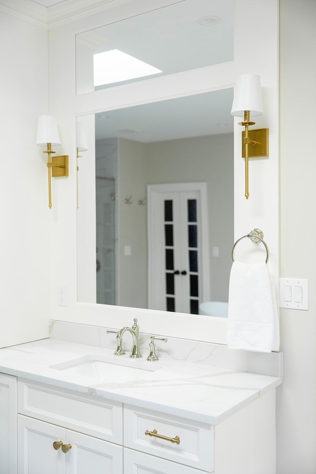 A bathroom with two sinks , a mirror and two lights.