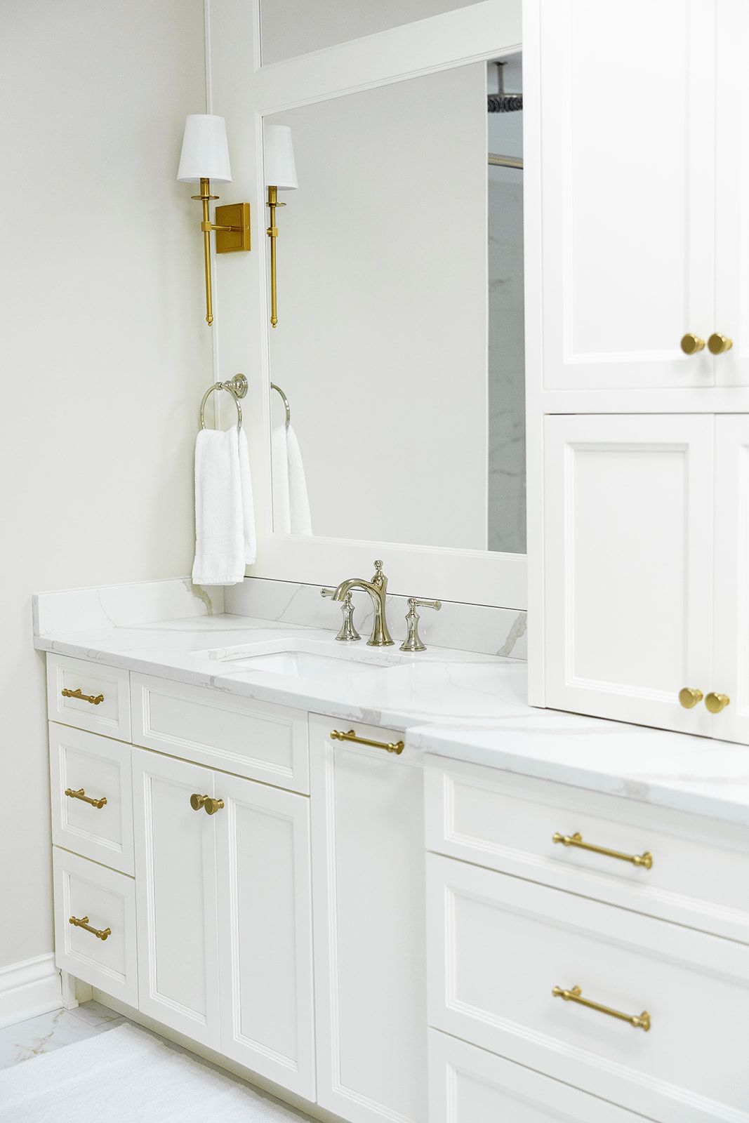 A bathroom with white cabinets , a sink and a mirror.