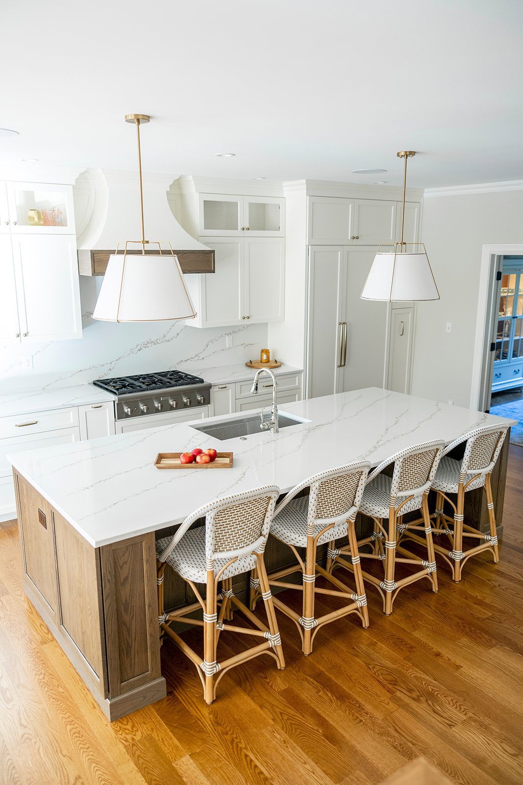 A kitchen with a large island and wicker chairs.
