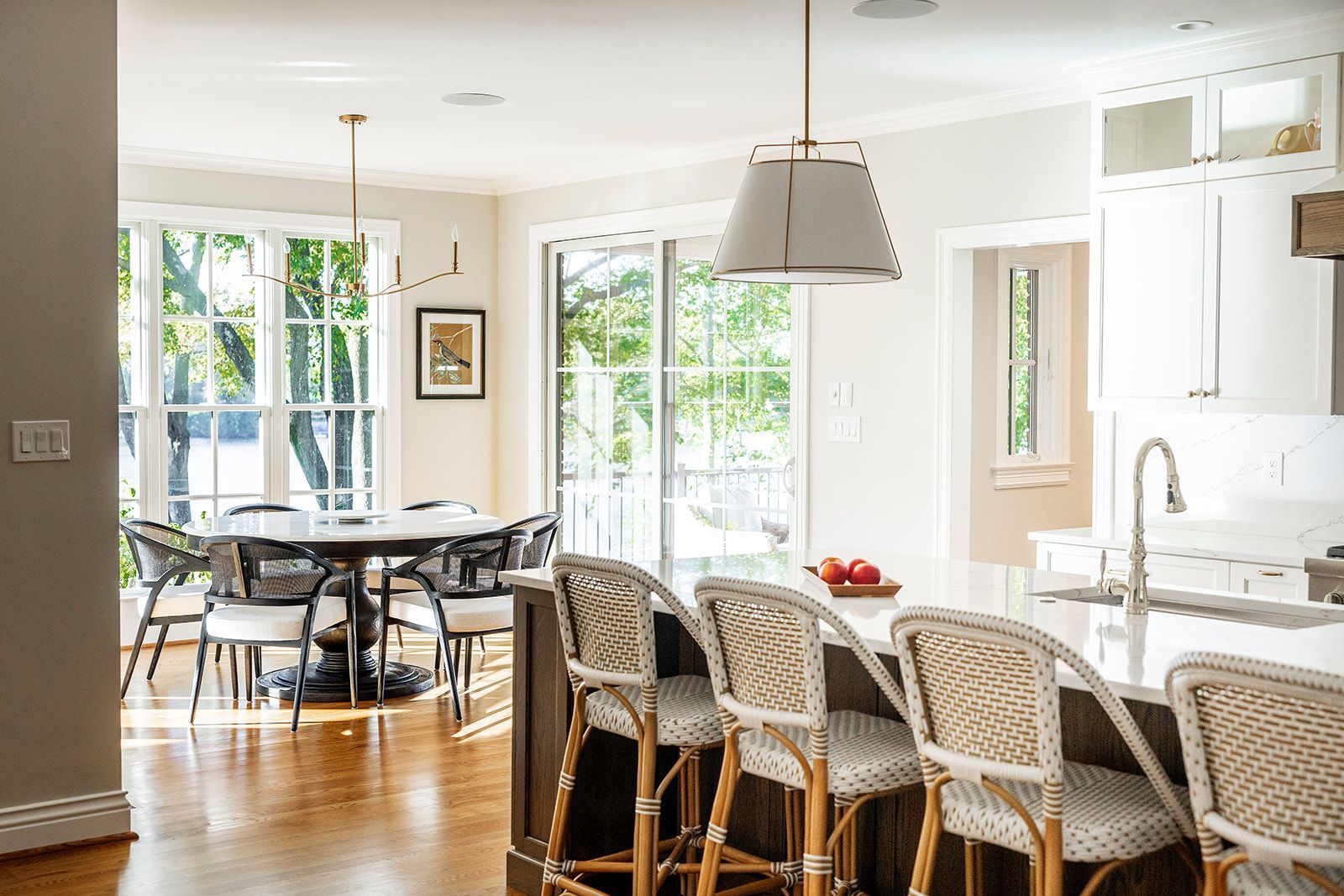 A kitchen with a table and chairs and a dining room in the background.