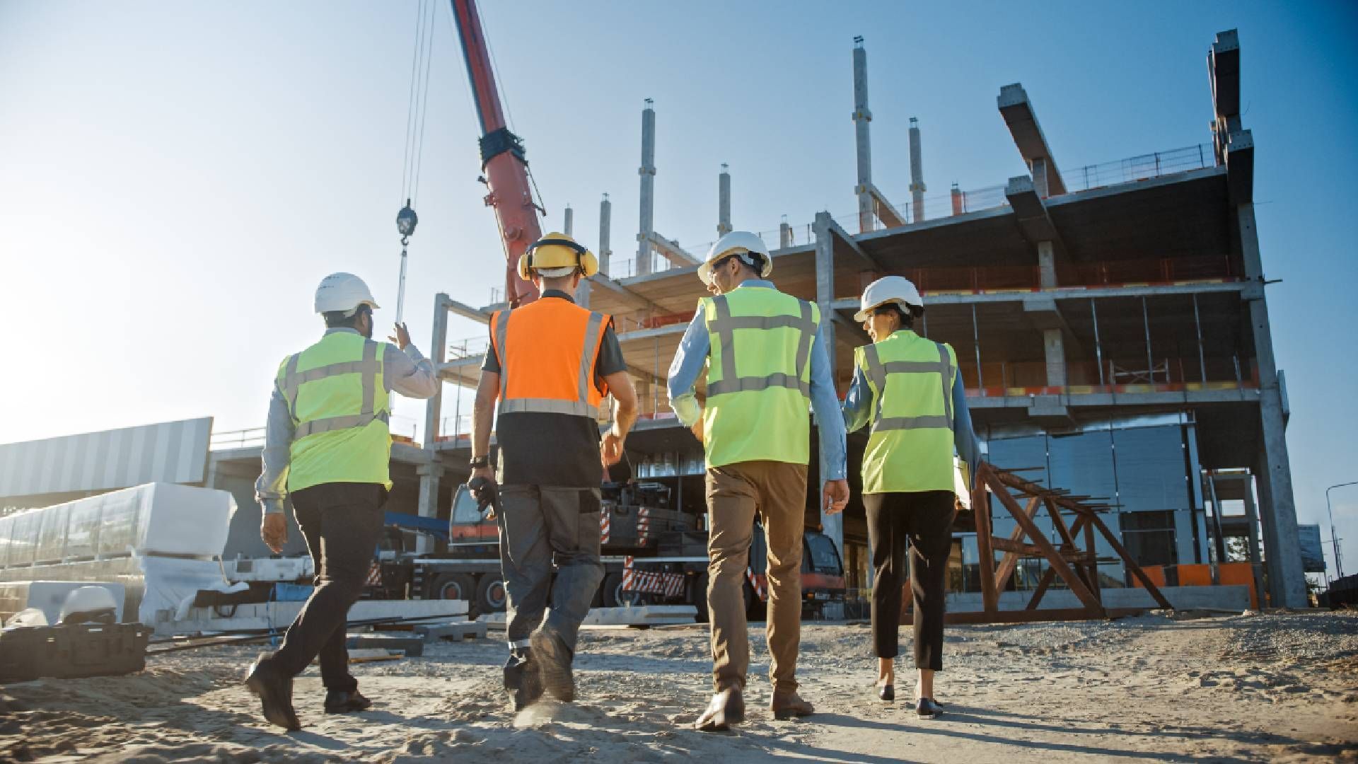 A group of construction workers are walking on a construction site.