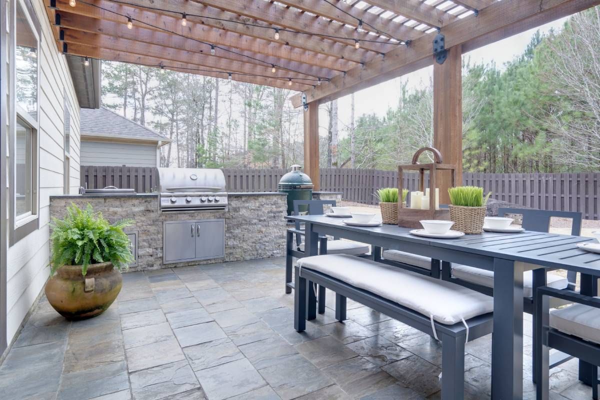 A patio with a table and benches and a grill.
