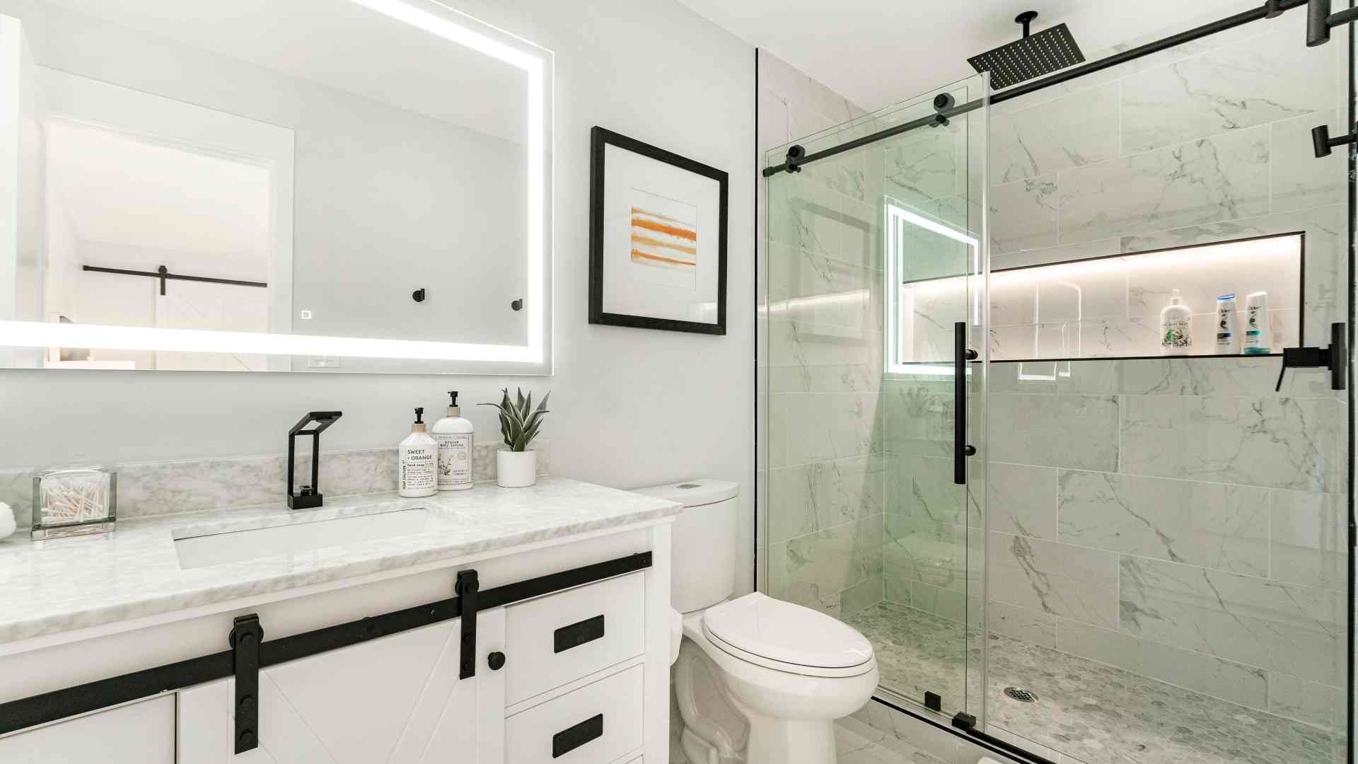 A bathroom with a toilet , sink , mirror and shower.