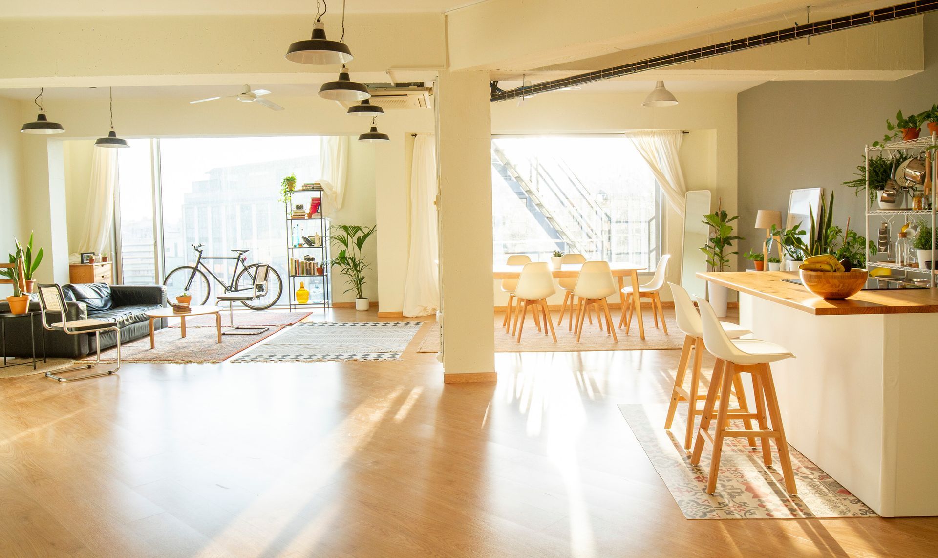 Bright, open-plan loft space with hardwood floors, kitchen island, dining table, and living room with a bicycle.