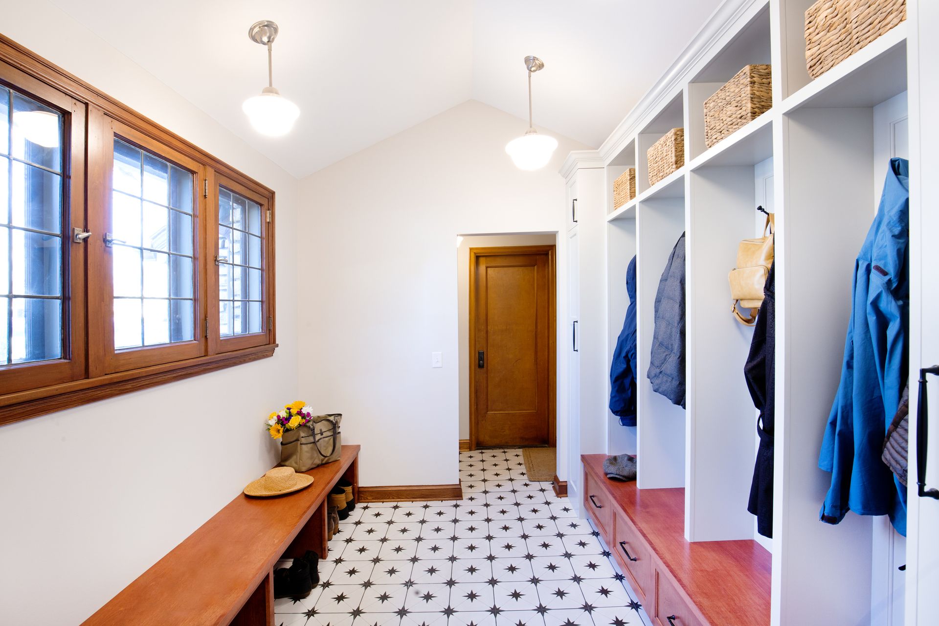 Mudroom with built-in storage lockers, bench, and decorative patterned tile flooring.