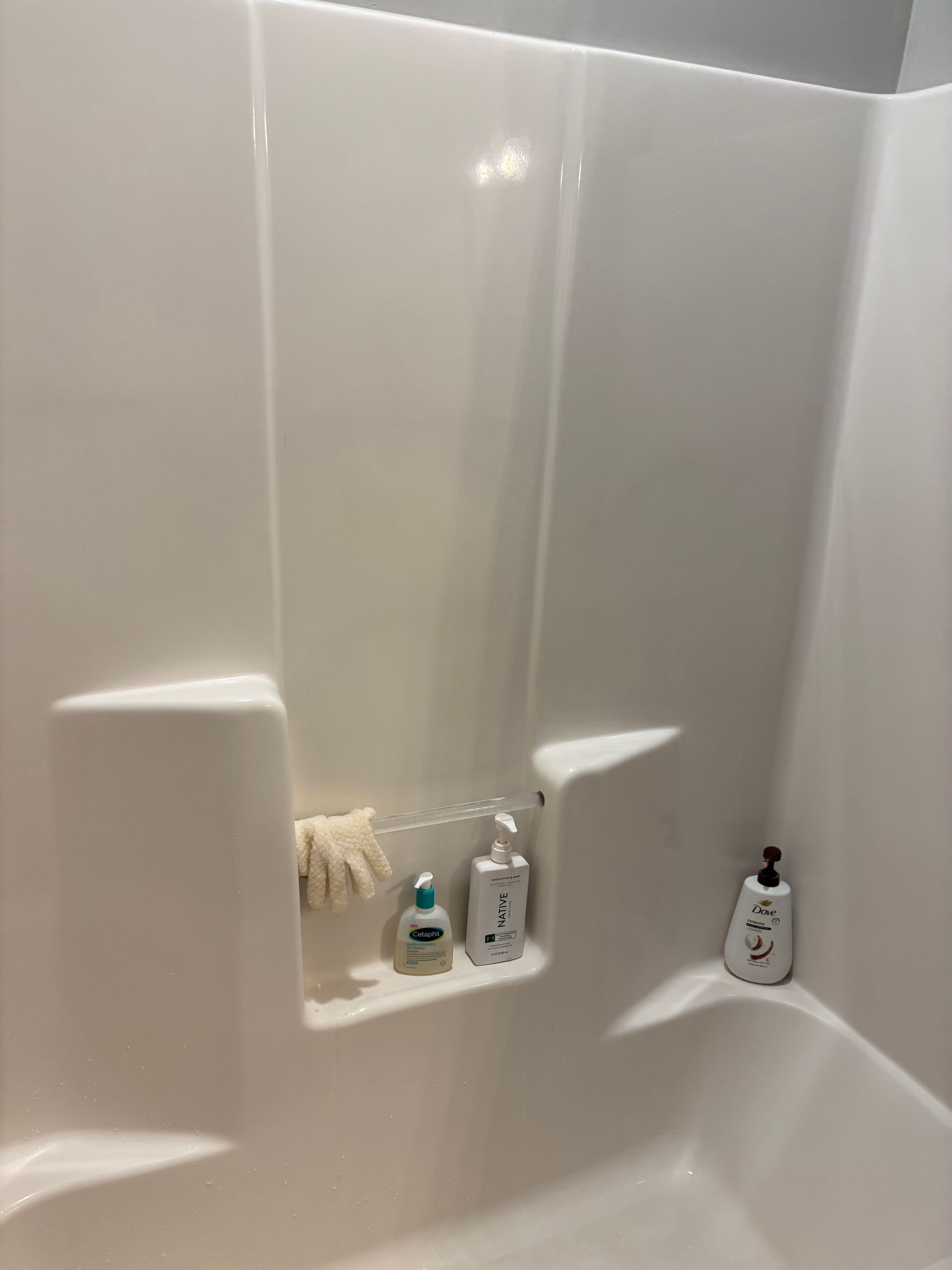 Woman wearing a mask and gloves, cleaning a window with a spray bottle and cloth.