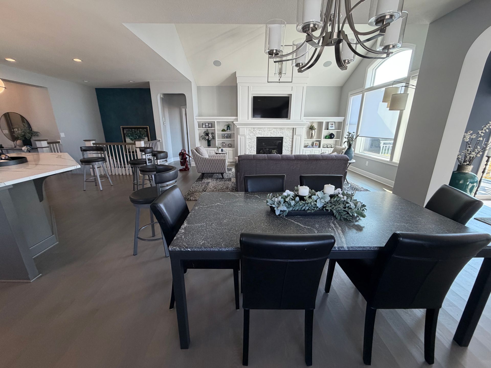 Cozy living room with sectional sofa, ottoman, and staircase. Neutral tones, lots of light.