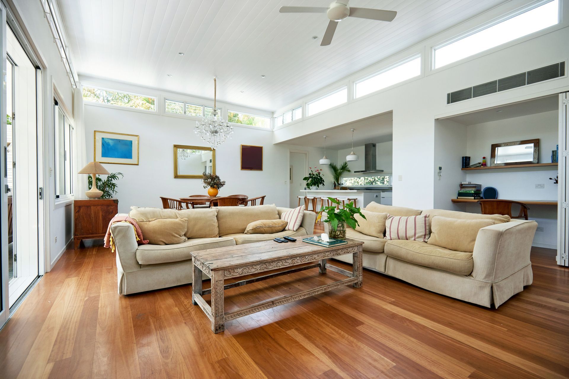 Bright living room with wooden floors, cream sofas, and a dining area.